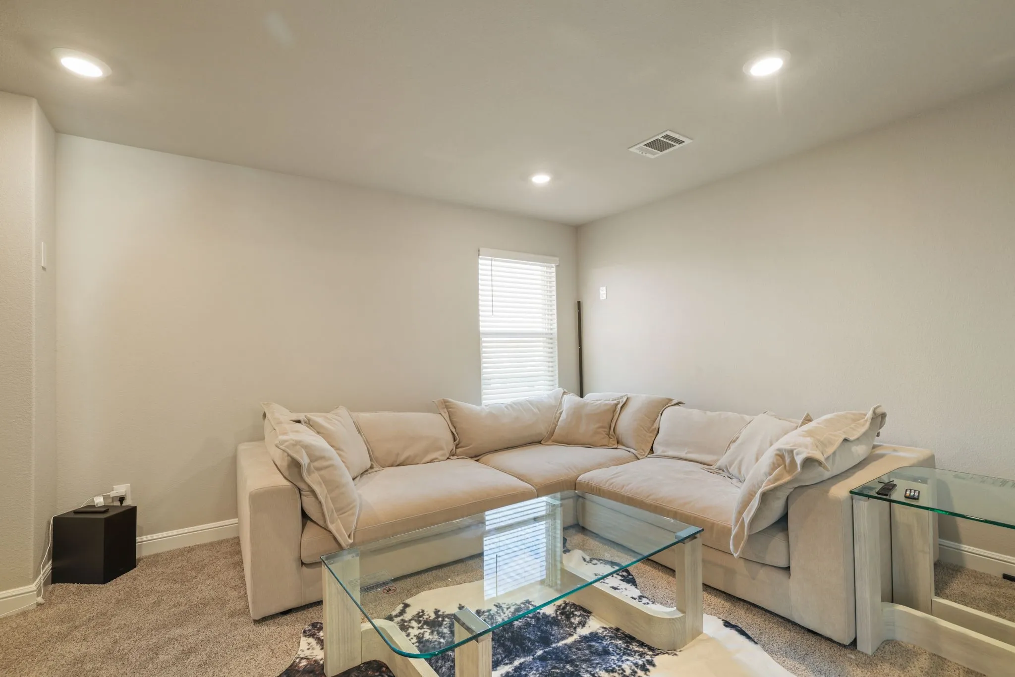 Living area with light colored carpet and recessed lighting