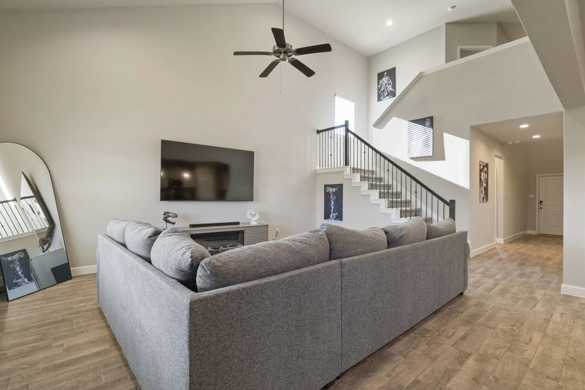 Living room featuring light wood-style floors, a ceiling fan, a fireplace, and vaulted ceiling
