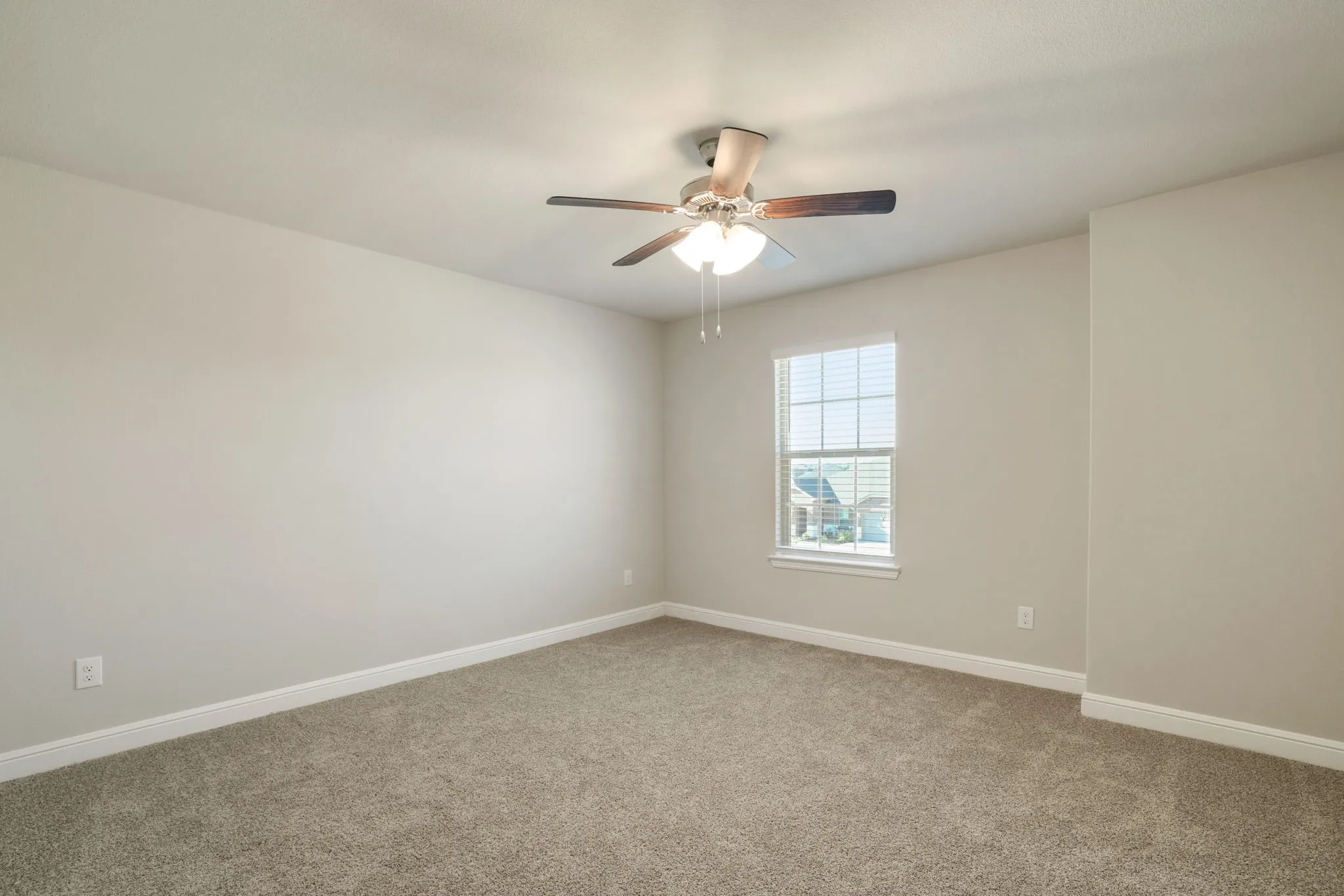 Carpeted spare room with baseboards and ceiling fan