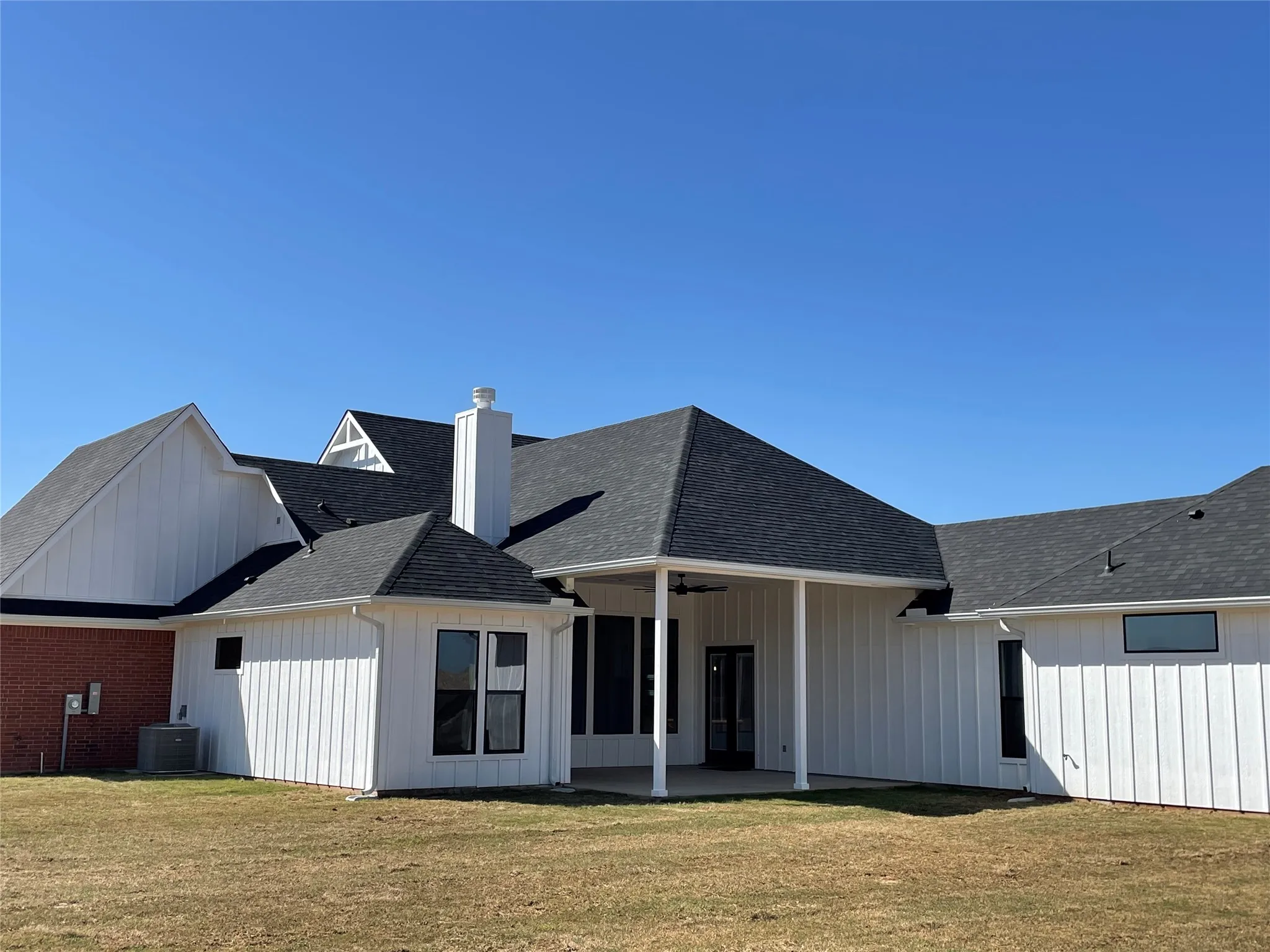 Back of property featuring a patio area, roof with shingles, ceiling fan, a yard, and a chimney