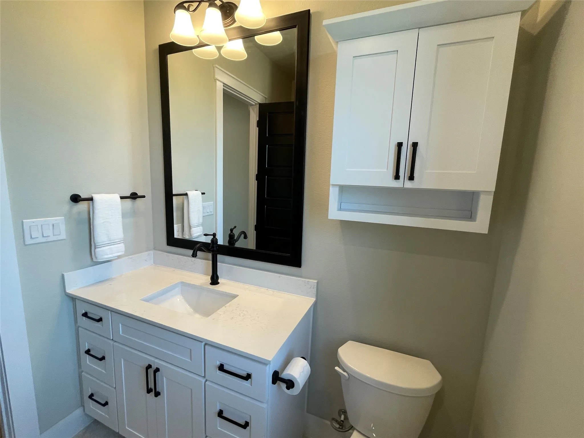 White shaker vanity with a light-toned countertop, undermount sink, and matte black faucet