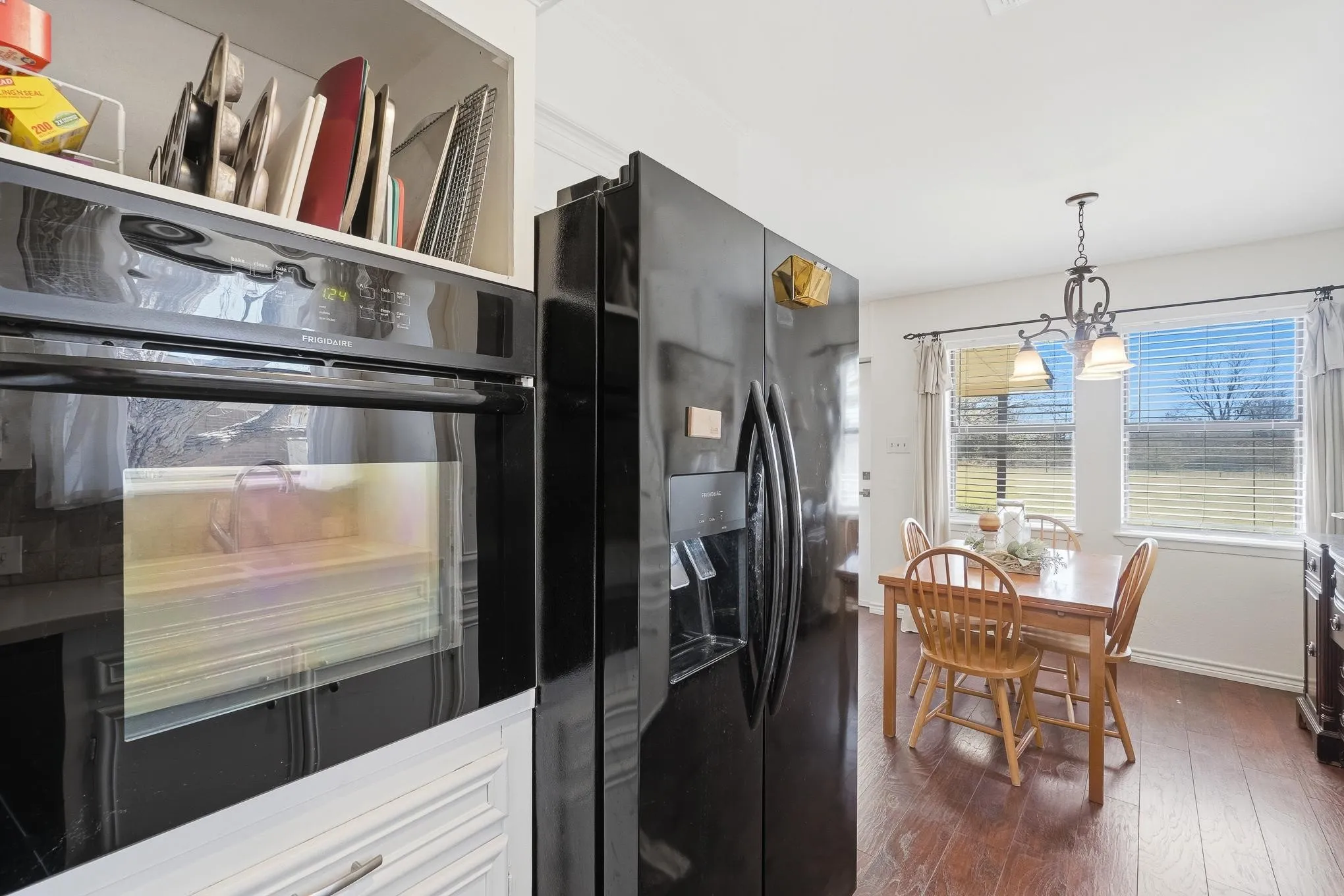 Kitchen featuring black appliances, dark wood-type flooring, pendant lighting, and white cabinetry