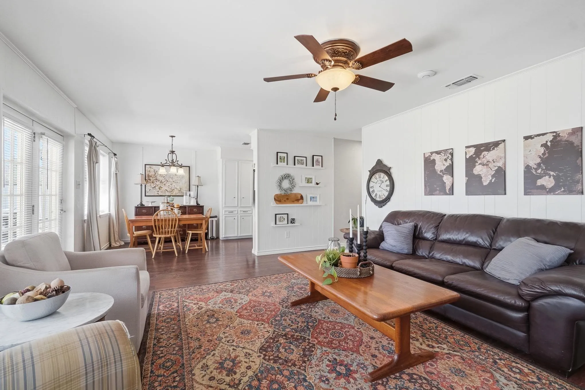 Living room with dark wood-type flooring, ceiling fan, and a chandelier