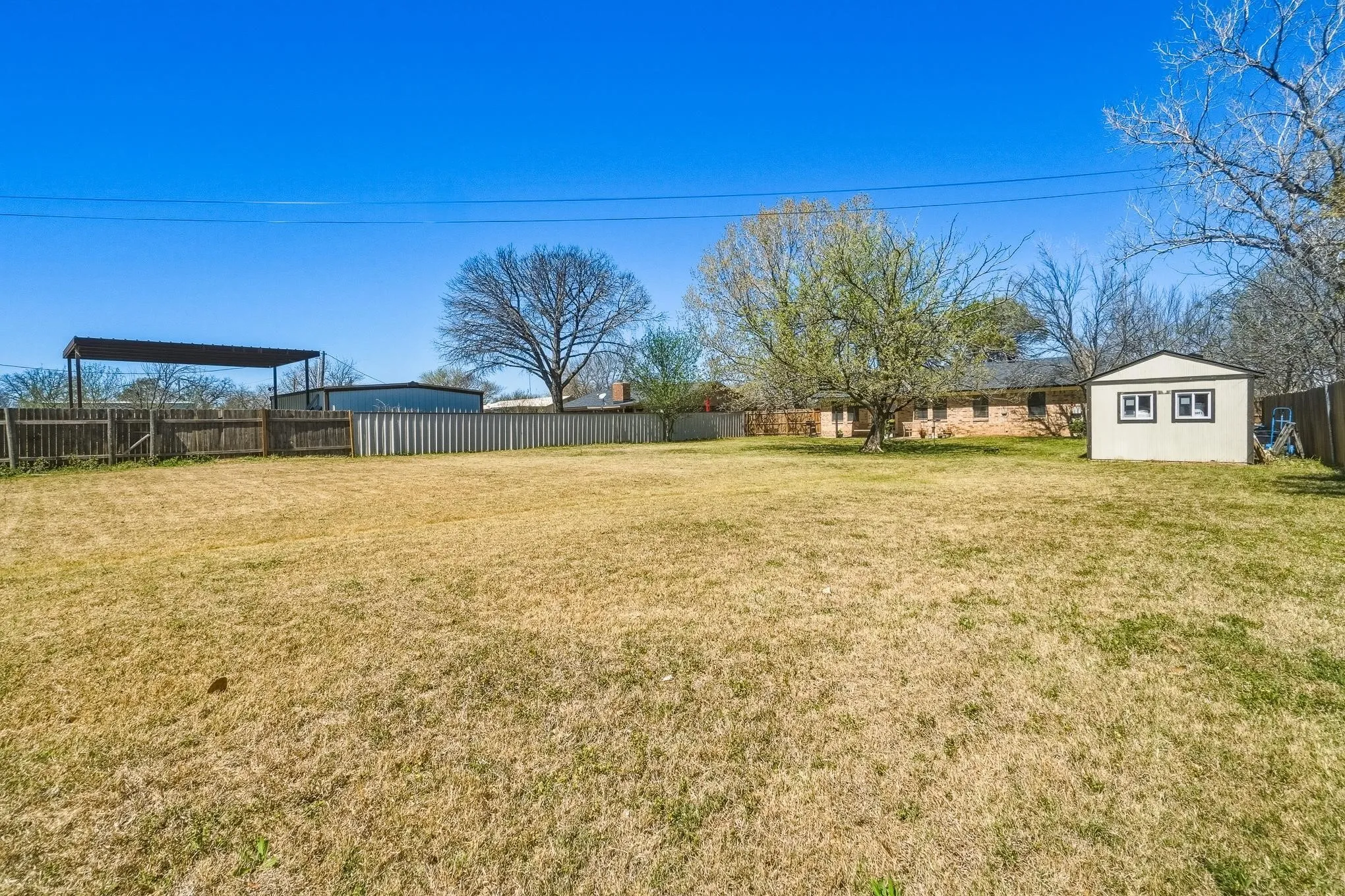 Fenced backyard featuring an outbuilding