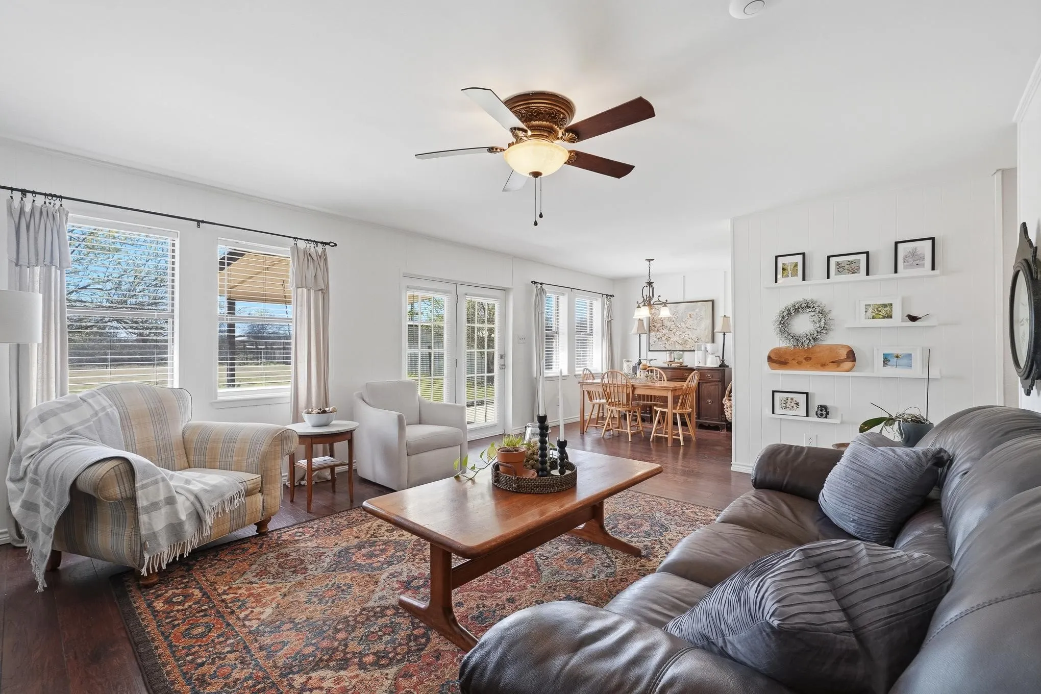 Living room featuring ceiling fan, dark wood-type flooring, and hanging lights