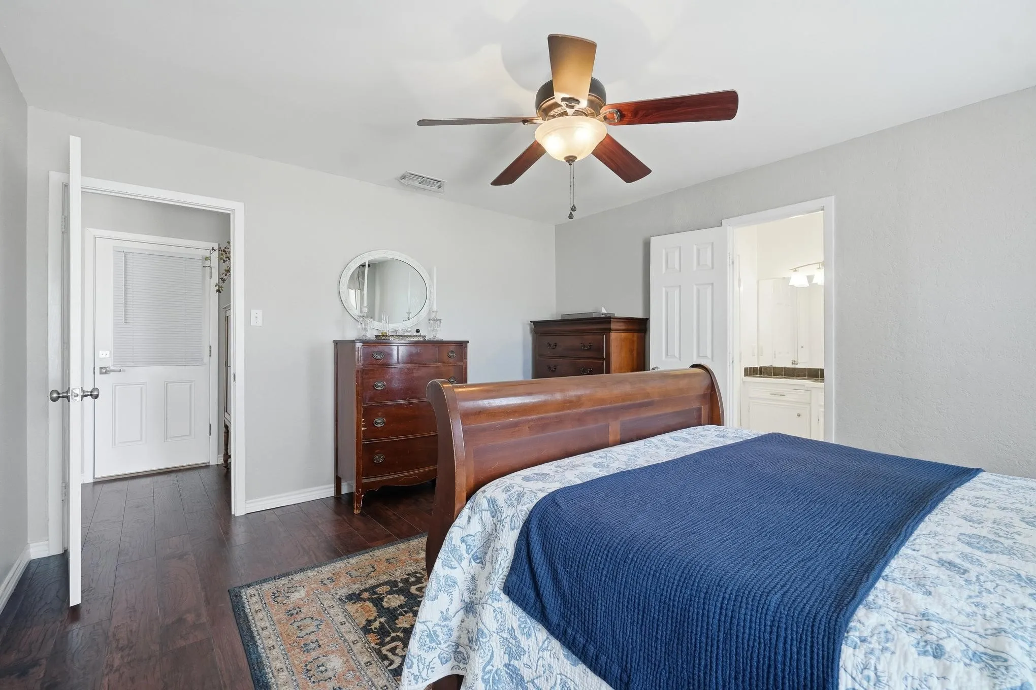 Bedroom featuring dark wood-style flooring, a ceiling fan, and connected bathroom