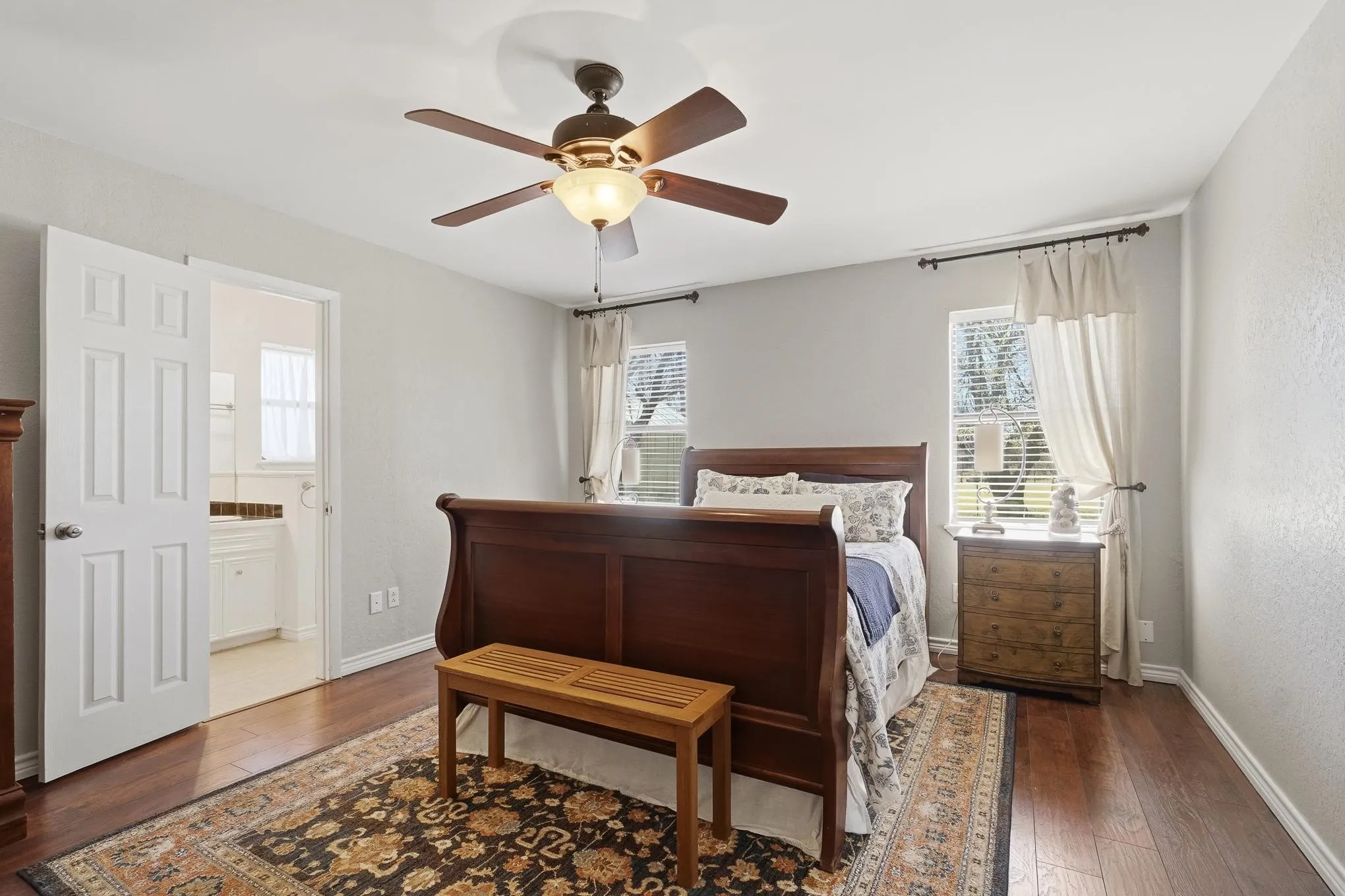 Bedroom featuring dark wood-style floors, a ceiling fan, and ensuite bathroom