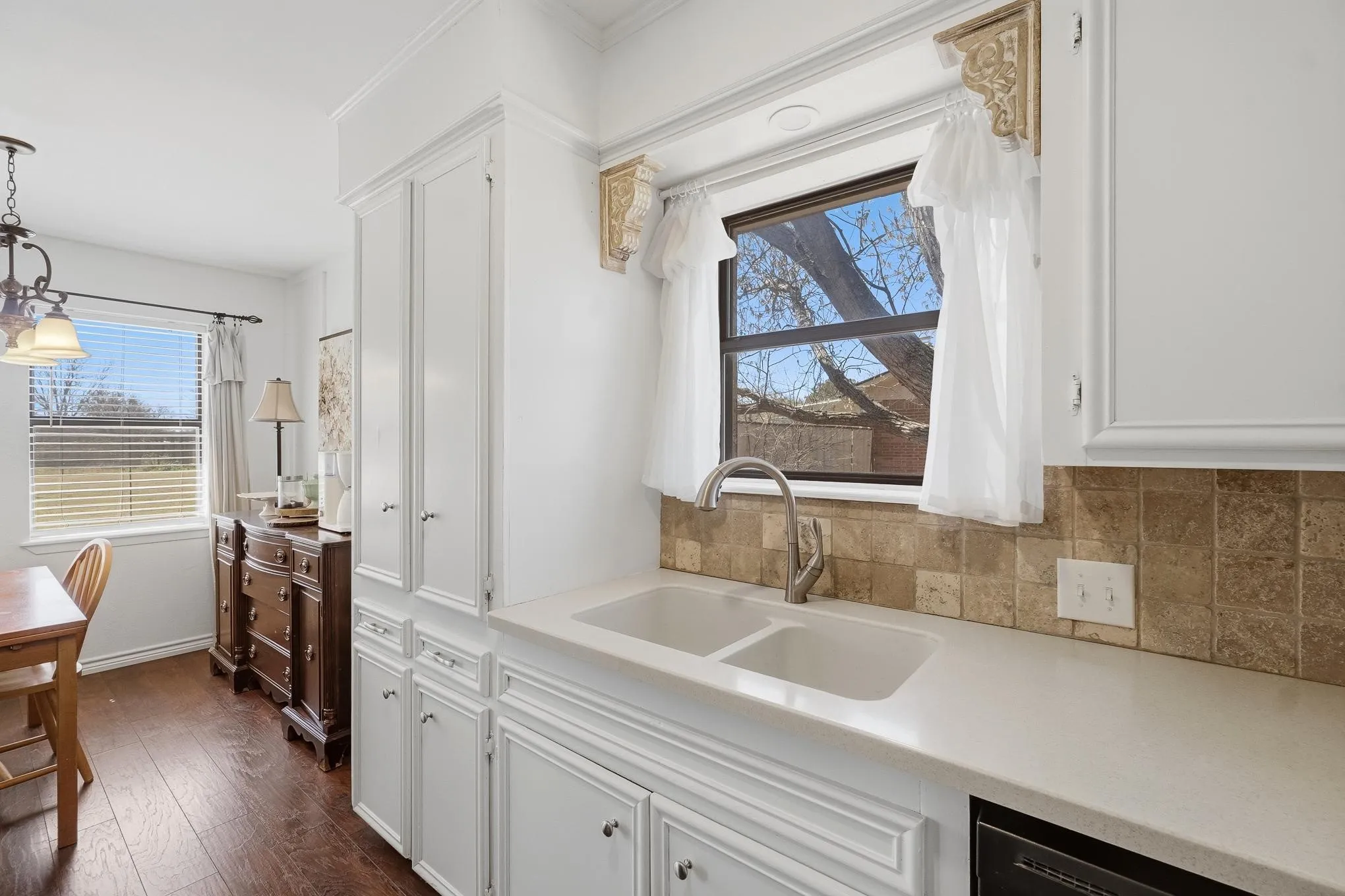 Kitchen with white cabinets, dark wood-style floors, pendant lighting, and decorative backsplash