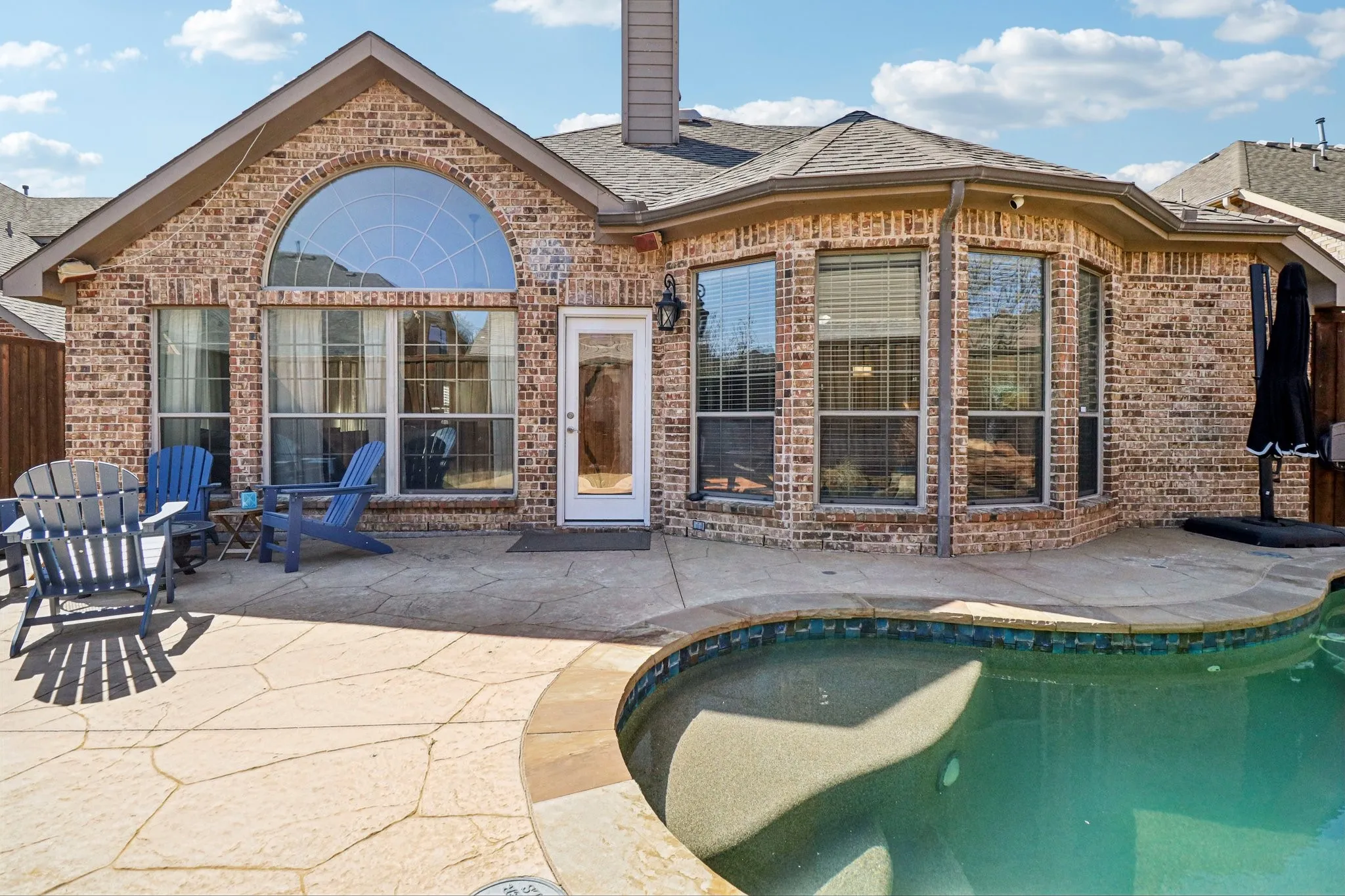 Rear view of property featuring an outdoor pool, a patio area, and brick siding