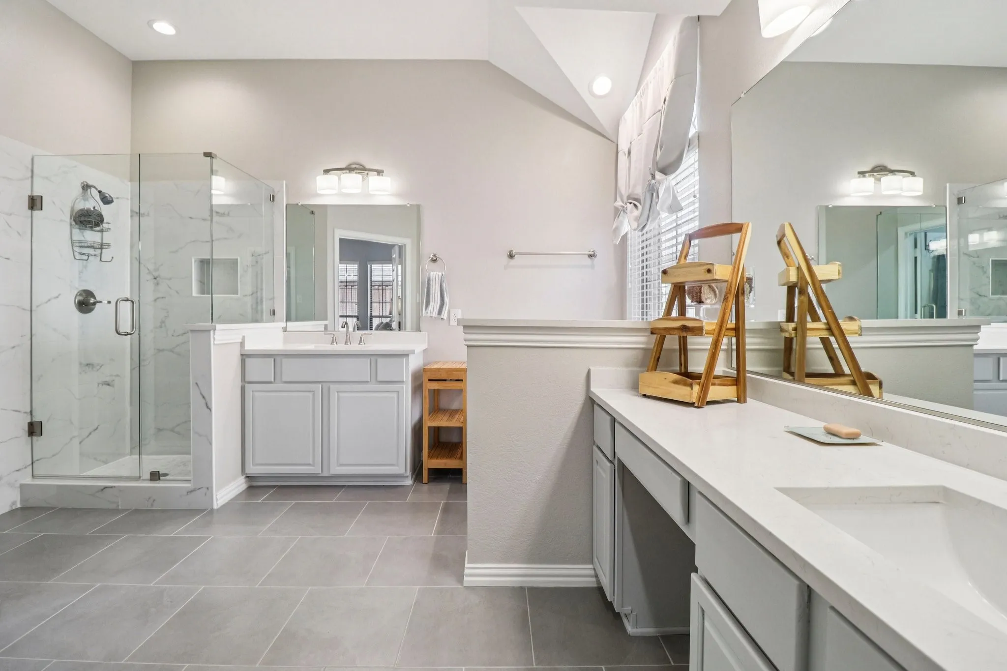 Bathroom featuring two vanities, a marble finish shower, and recessed lighting
