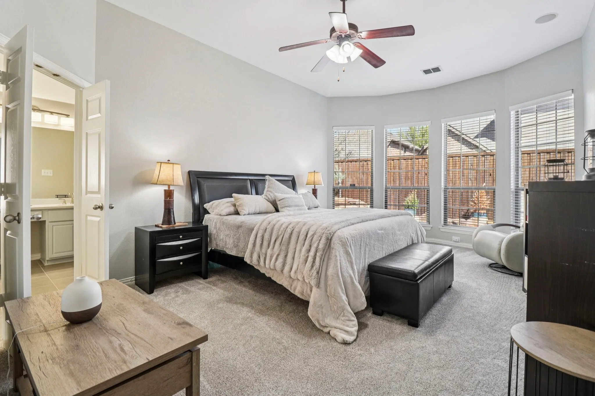 Bedroom featuring light colored carpet, connected bathroom, and ceiling fan