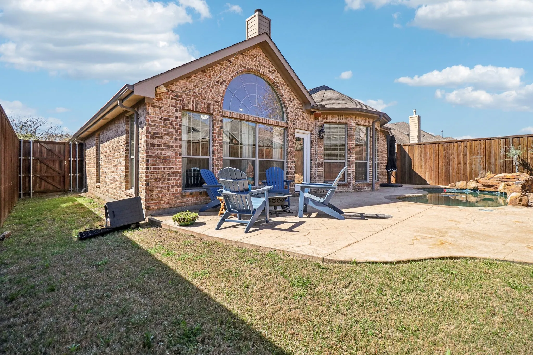 Back of house with a fenced backyard, brick siding, a gate, and a patio area