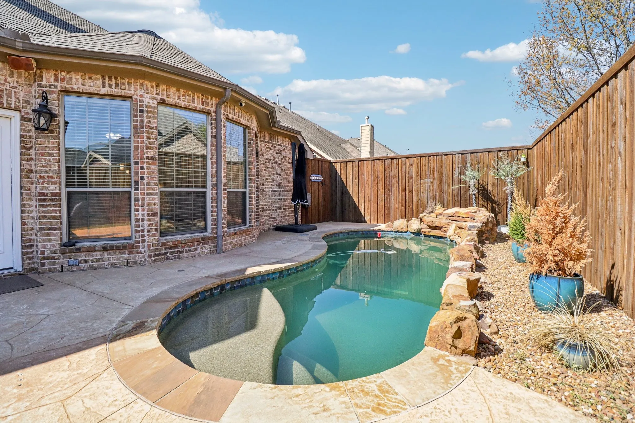 View of pool featuring patio surround and a fenced backyard