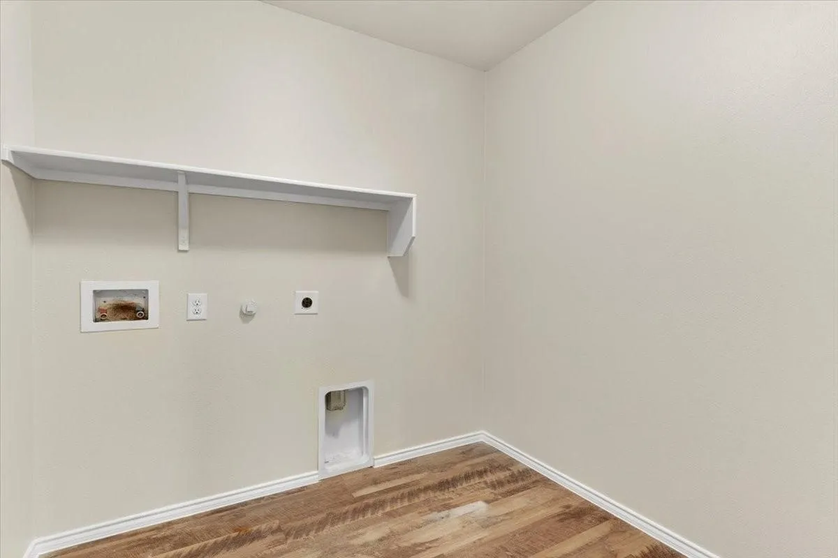 Dedicated utility area featuring a wall-mounted shelf, electrical outlet, and plumbing connections for appliances
