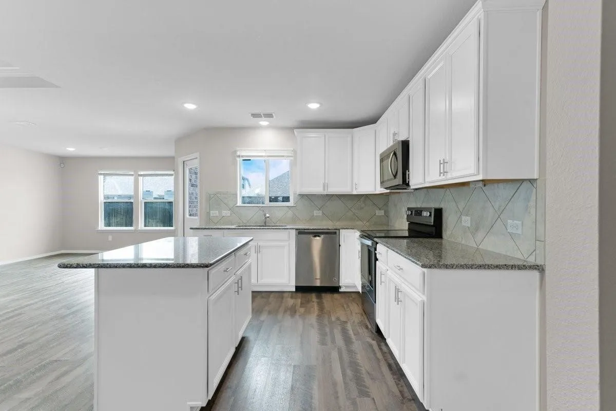 Modern kitchen featuring white cabinetry, granite countertops, stainless steel appliances, a tile backsplash, and wood-finish flooring