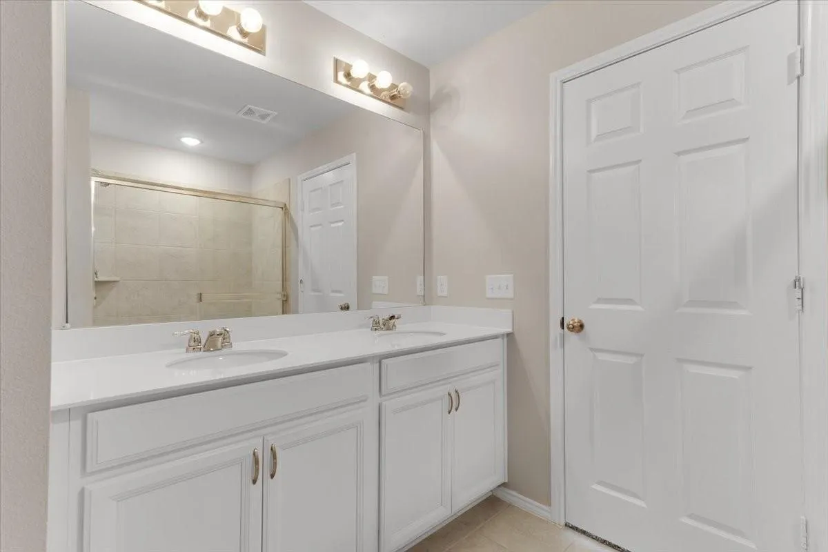 Dual vanity with white cabinetry and integrated sinks, complemented by a large wall-mounted mirror