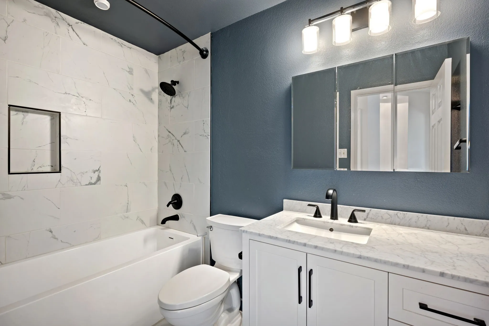 Full bathroom with a textured wall, vanity, and bathtub / shower combination