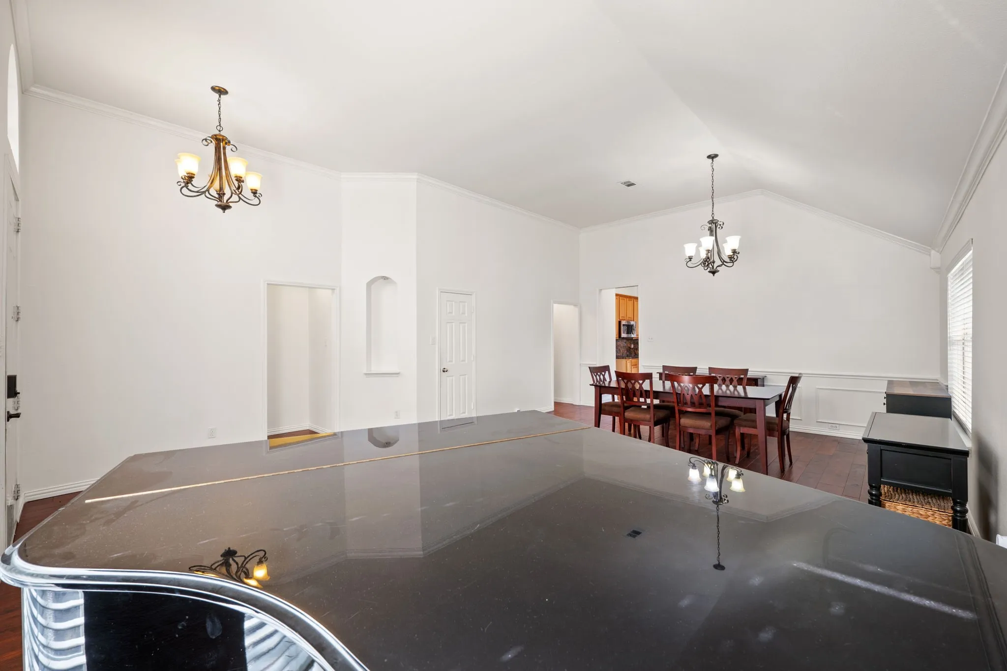 Kitchen featuring a chandelier, ornamental molding, dark wood-type flooring, vaulted ceiling, and a wainscoted wall