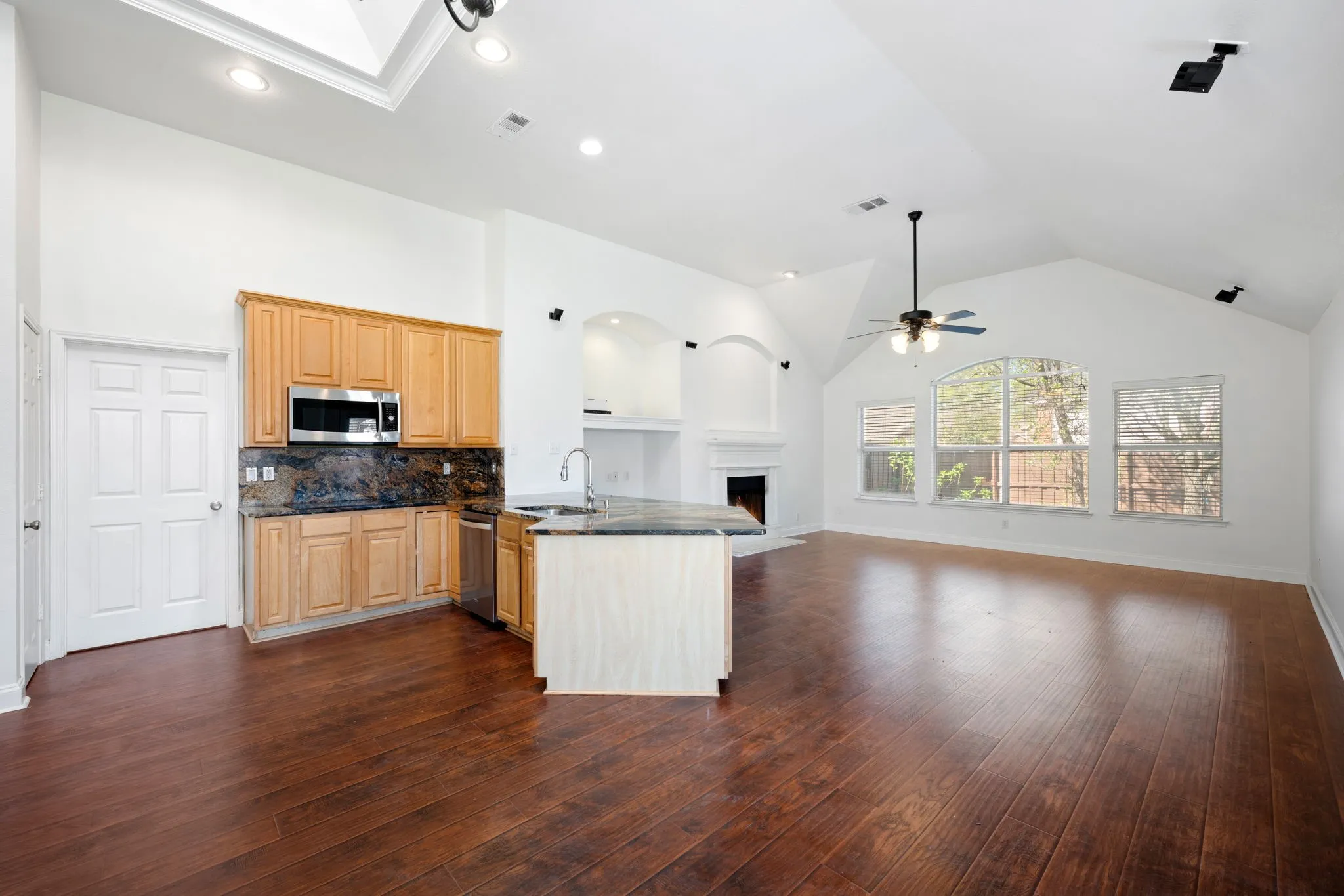 Kitchen with open floor plan, a peninsula, tasteful backsplash, a warm lit fireplace, and dark wood-style flooring