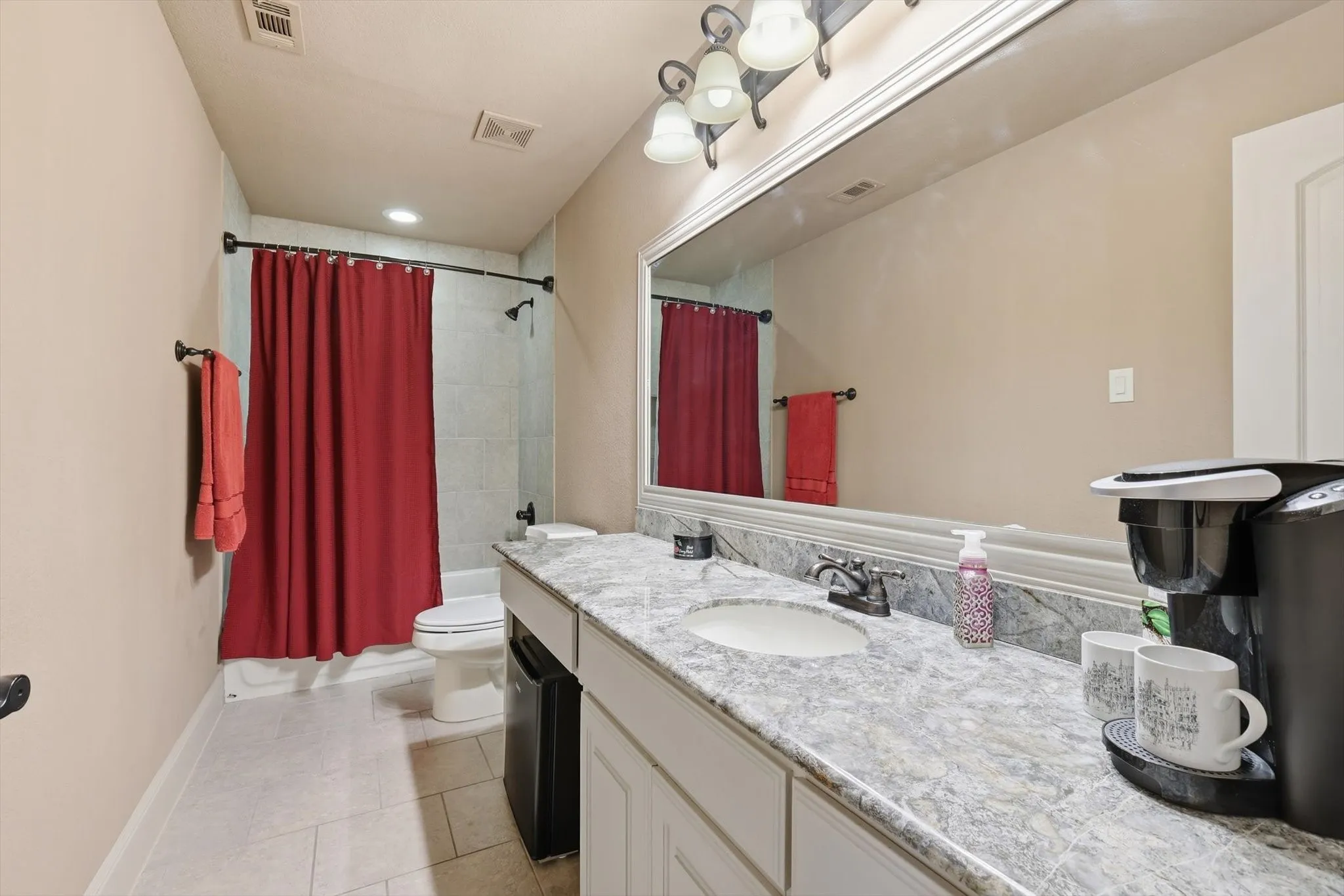 Bathroom with vanity, shower / bath combination with curtain, and light tile patterned floors