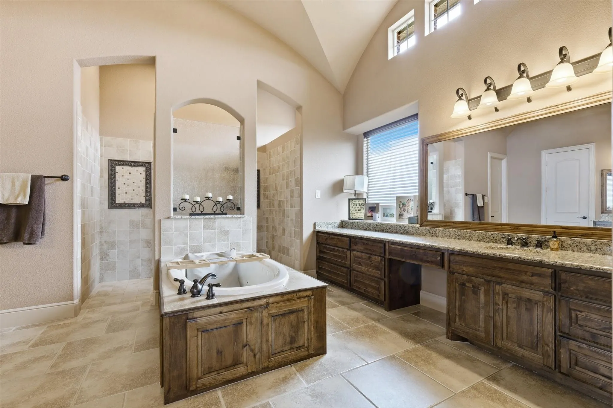 Full bath featuring vaulted ceiling, a garden tub, vanity, and a walk in shower