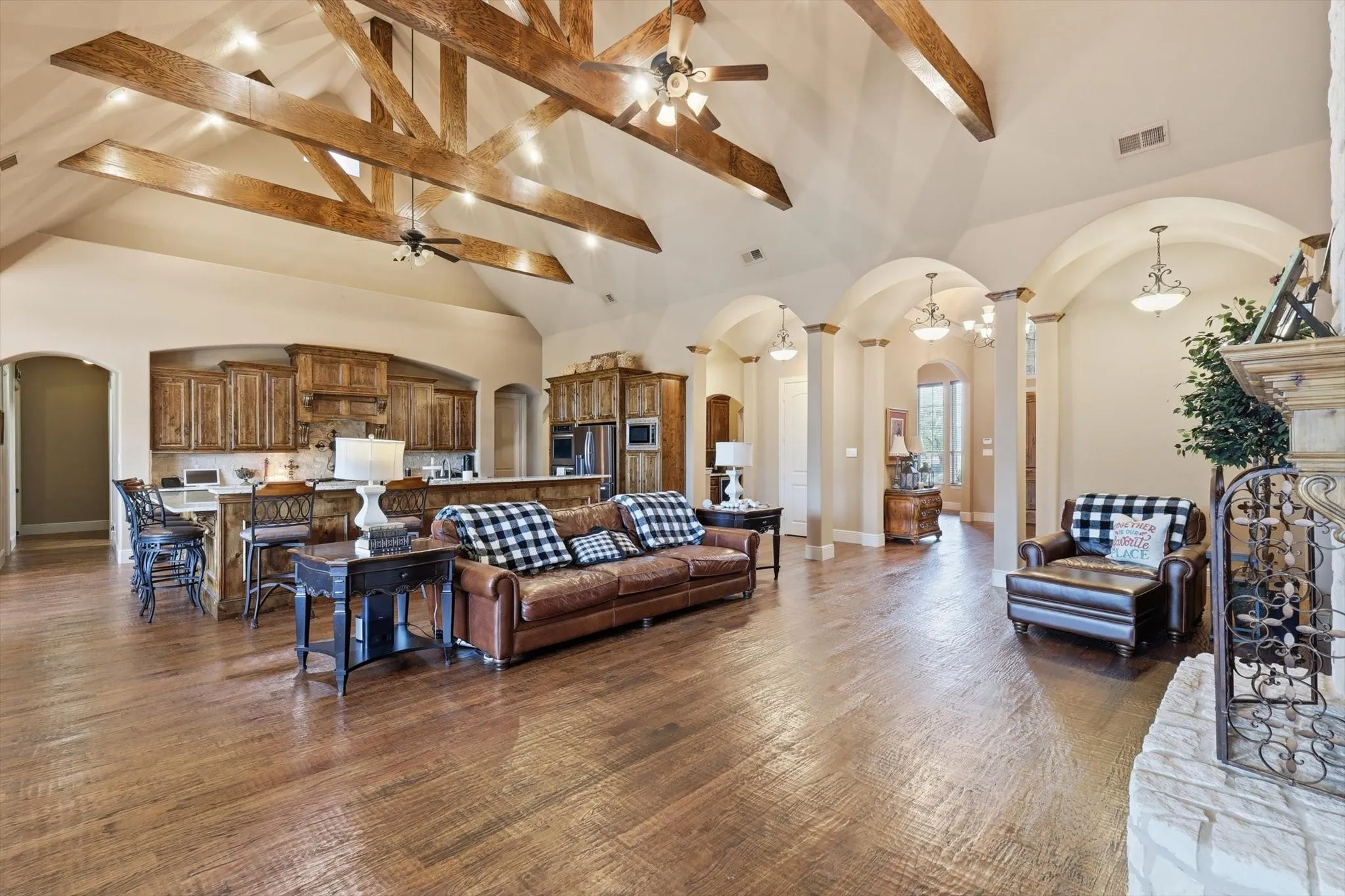 Living area with arched walkways, a ceiling fan, dark wood-style flooring, and lofted ceiling