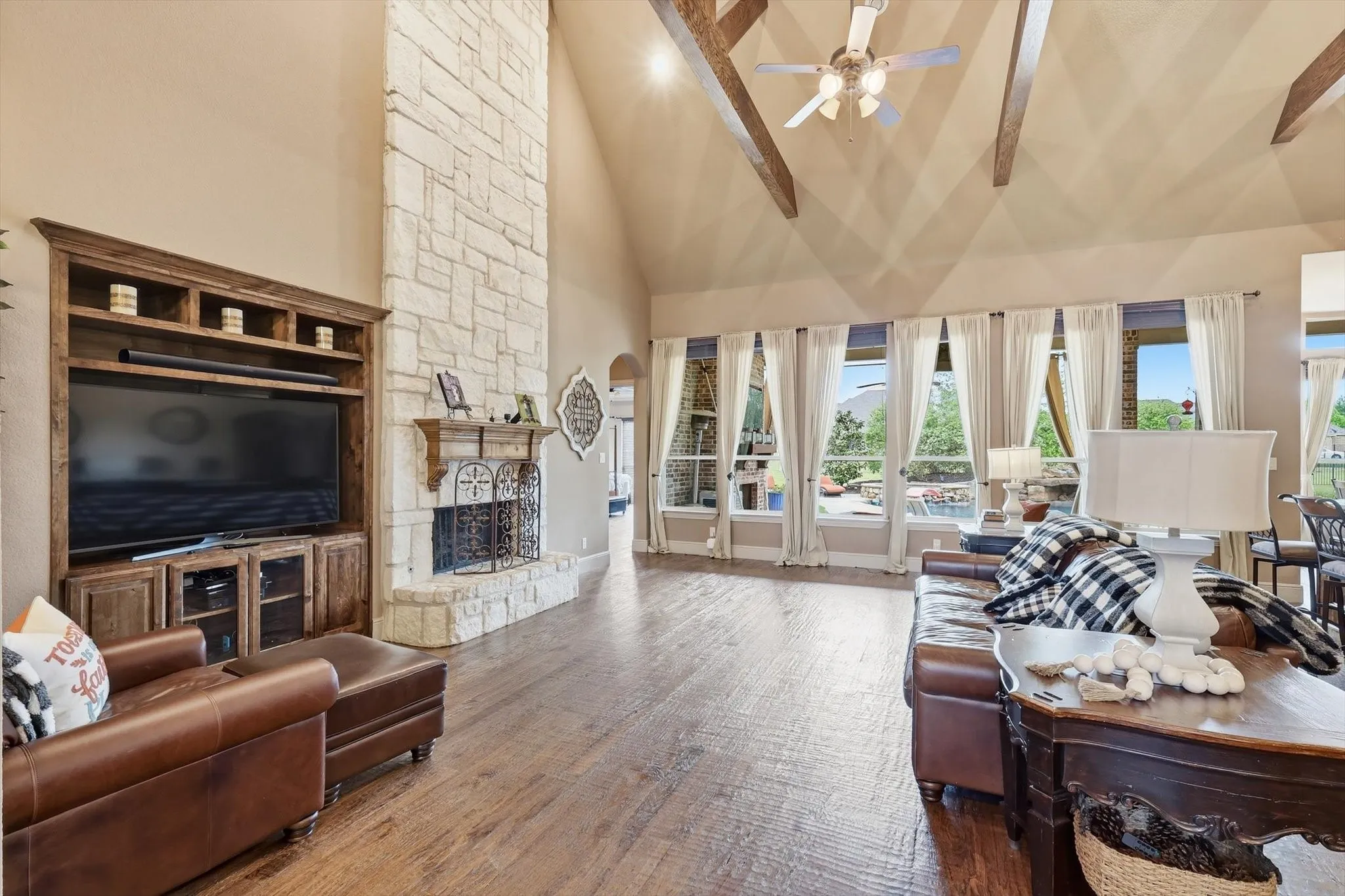 Living area featuring a stone fireplace, lofted ceiling, ceiling fan, and wood-type flooring