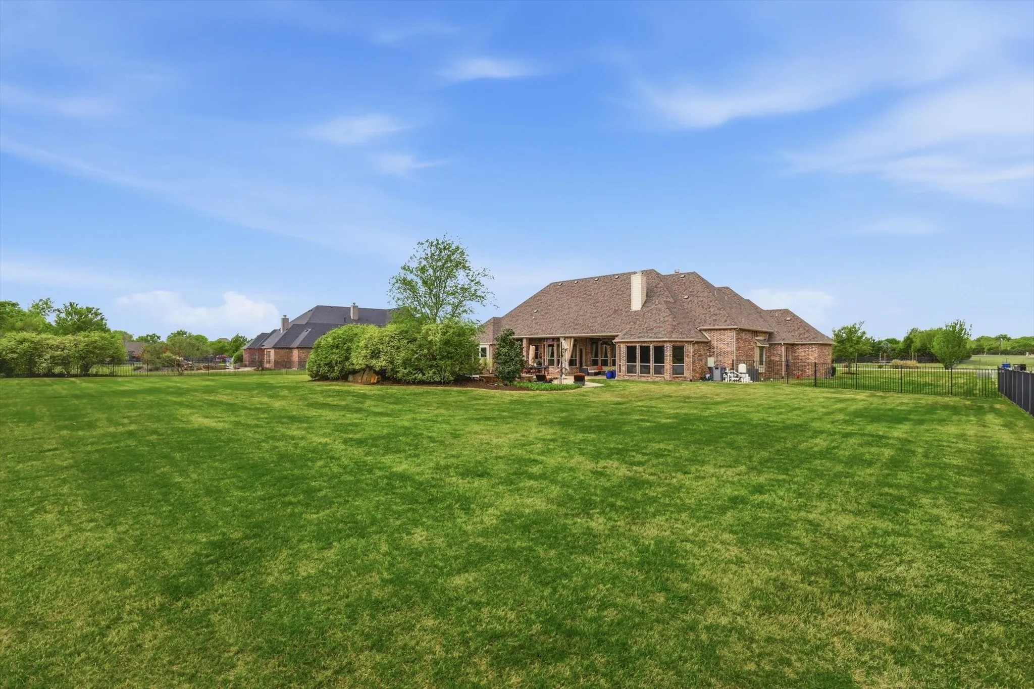 Back of property with a fenced backyard and brick siding