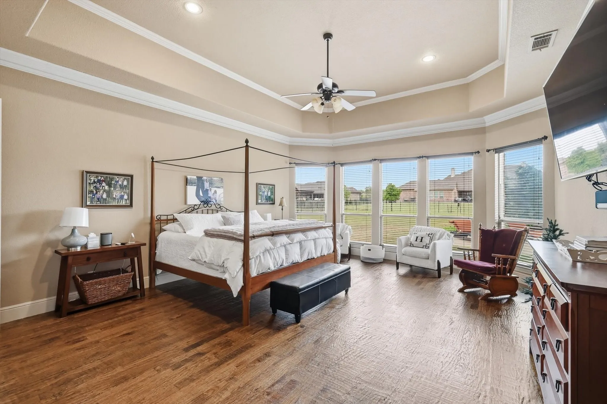 Bedroom featuring dark wood-style flooring, ceiling fan, a raised ceiling, and crown molding