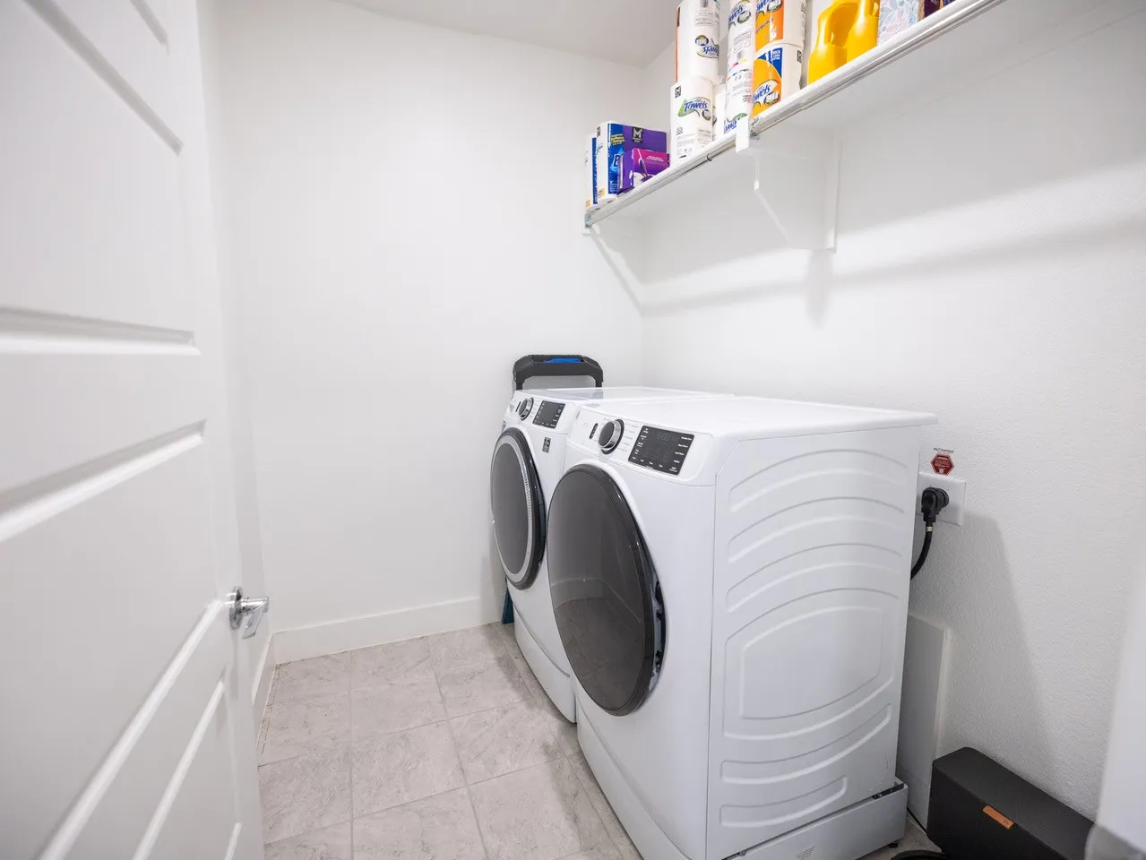 White paneled door, light-toned tile flooring, and wall-mounted shelving