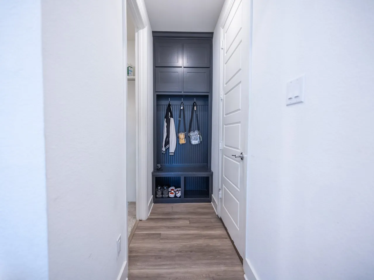 Built-in mudroom storage with cabinet doors, coat hooks, and bench seating