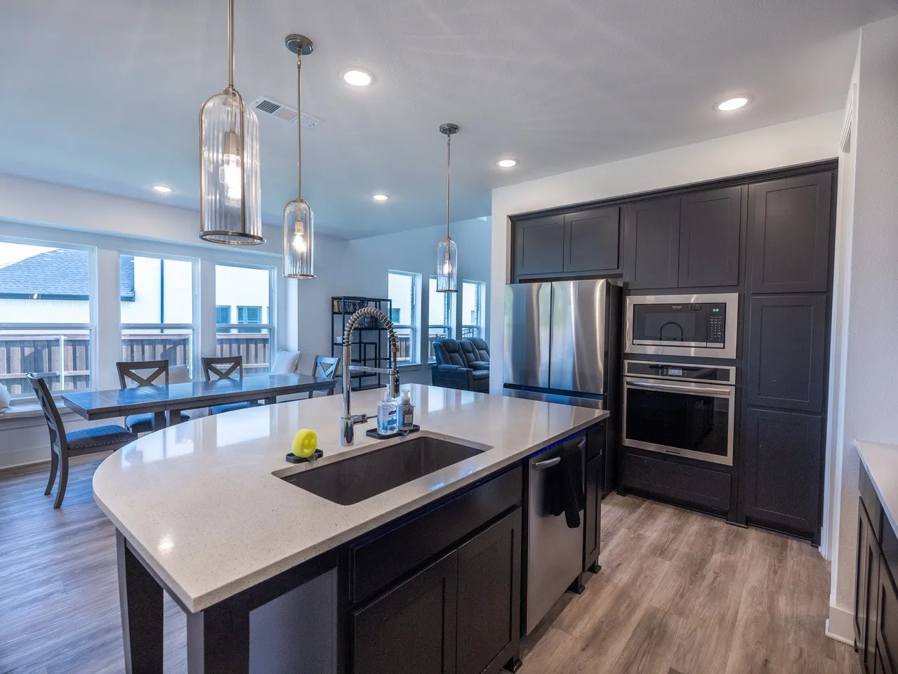 Kitchen island with a light-toned countertop, integrated sink, and gooseneck faucet