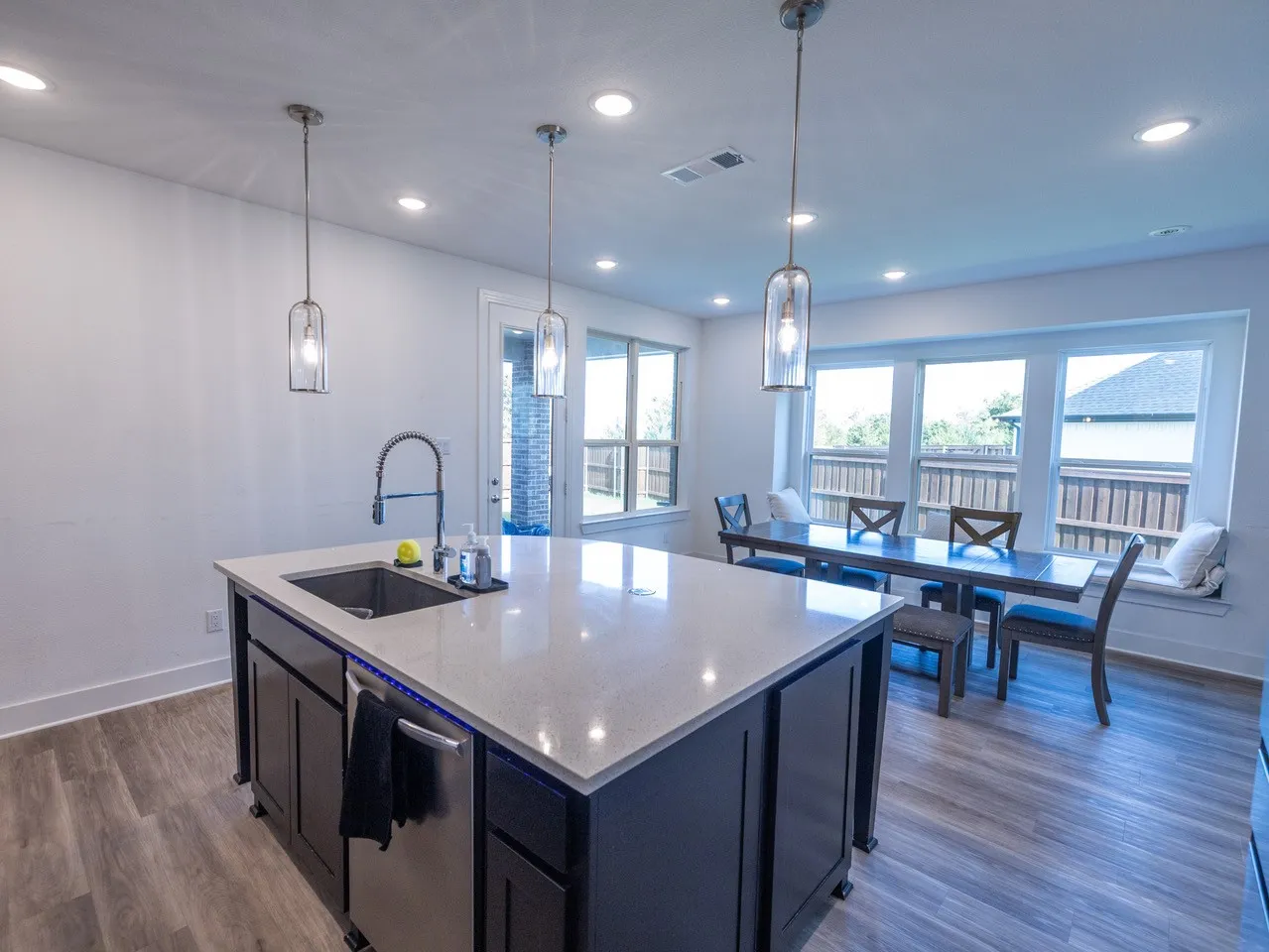 Kitchen island with a light-toned countertop, stainless steel sink, and integrated dishwasher