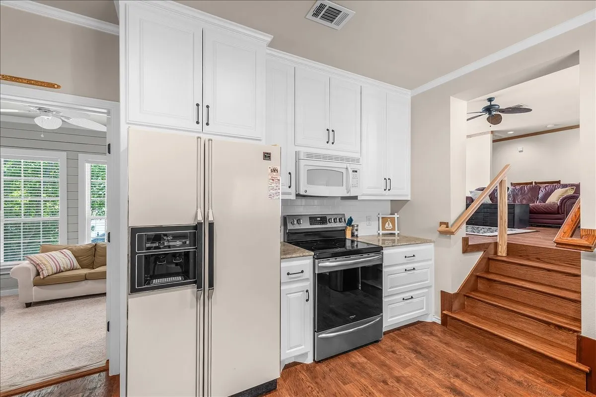 Kitchen featuring a ceiling fan, ornamental molding, white appliances, white cabinetry, and dark wood-style flooring