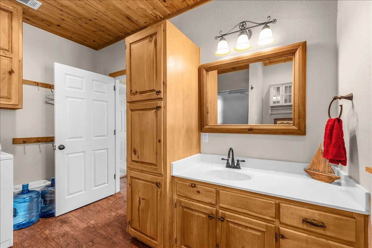 Full bathroom featuring vanity, wooden ceiling, dark wood-style flooring, and washer / dryer