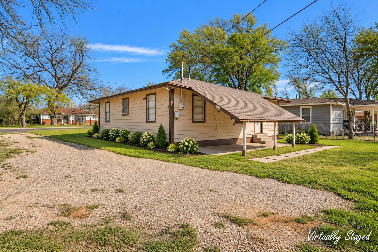 Siding exterior with a covered porch, gravel driveway, and landscaped shrubbery Virtually staged