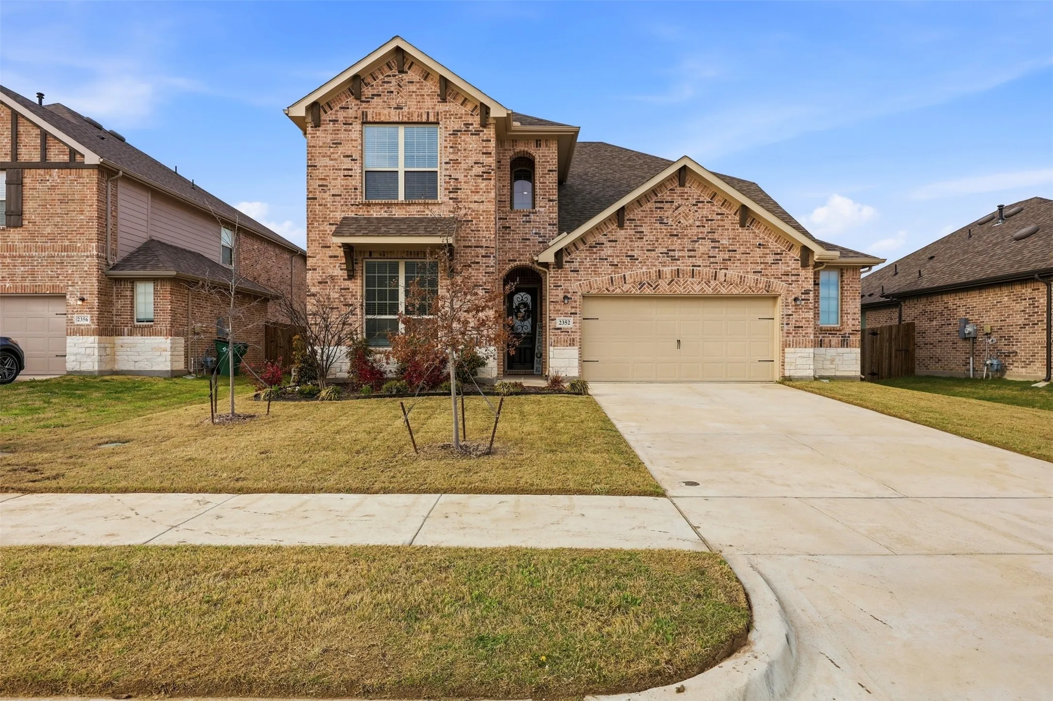 Traditional-style home featuring brick siding, a garage, and concrete driveway