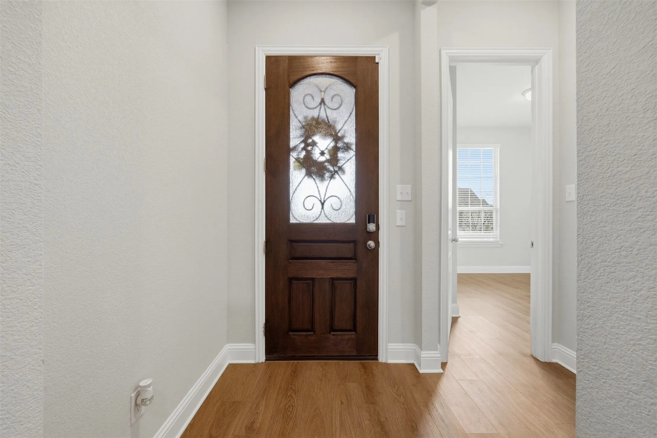 Foyer entrance featuring light wood-style floors and a textured wall