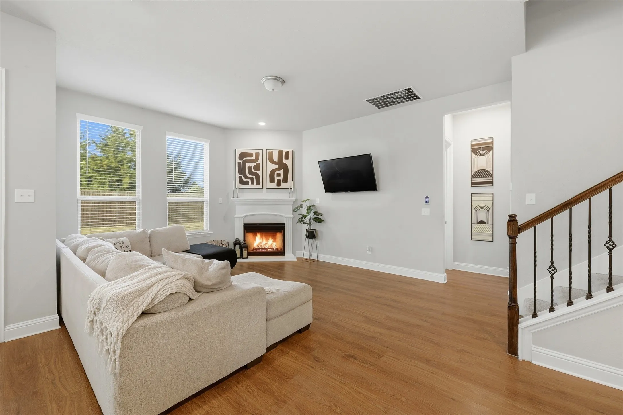 Living room with a lit fireplace, light wood-type flooring, and recessed lighting