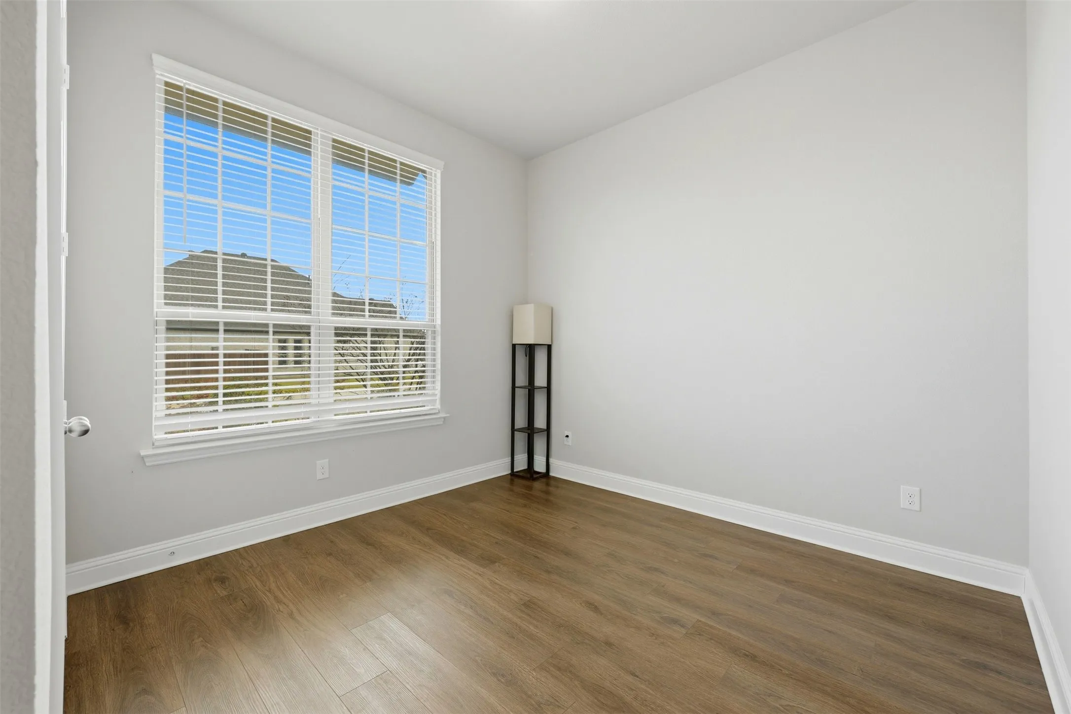 Downstairs secondary room with baseboards and dark wood-style flooring