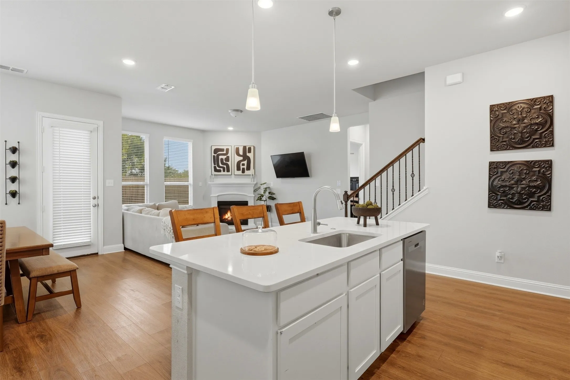 Kitchen featuring open floor plan, a center island with sink, white cabinetry, a lit fireplace, and light wood-type flooring