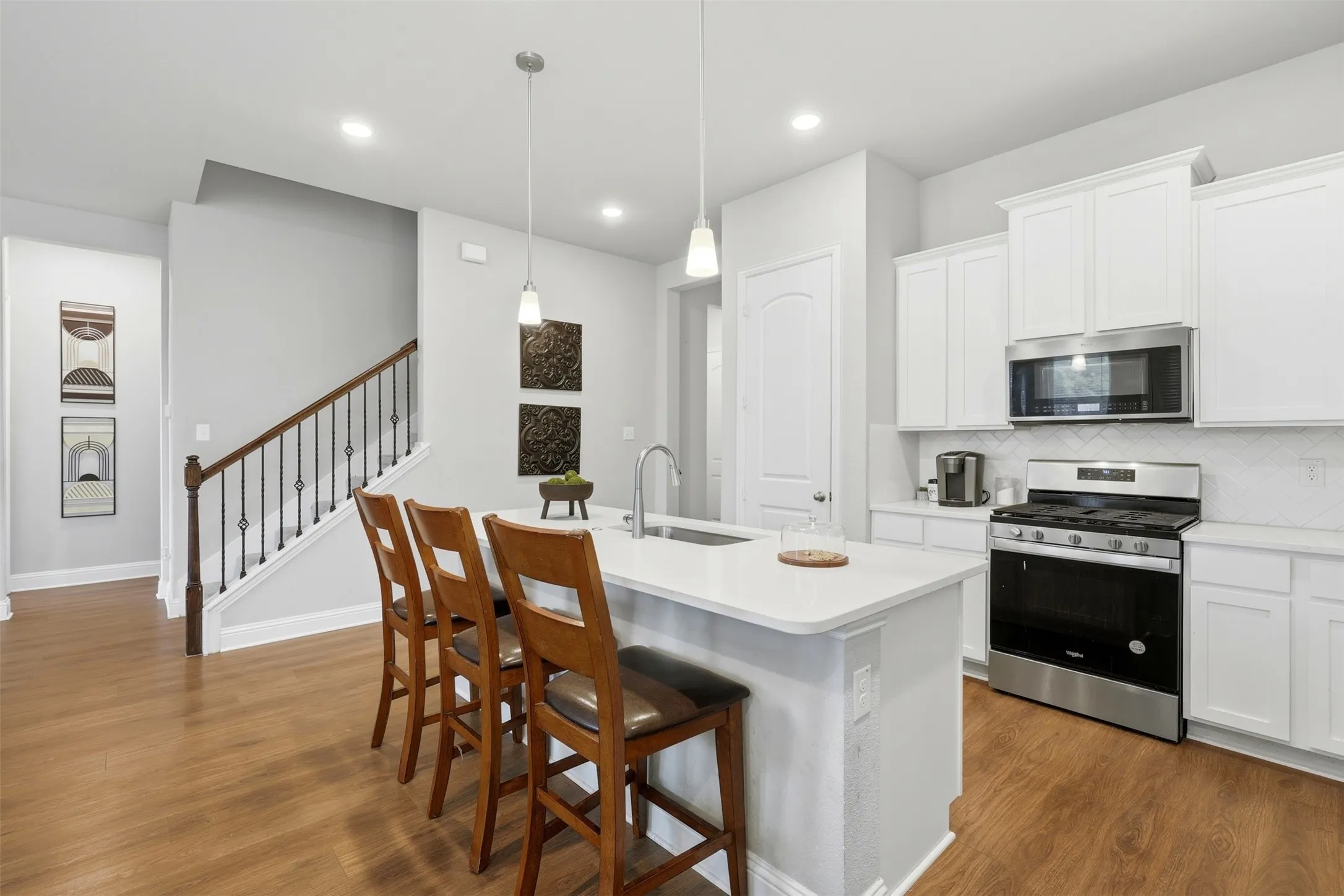 Kitchen with stainless steel appliances, a kitchen breakfast bar, and white cabinetry