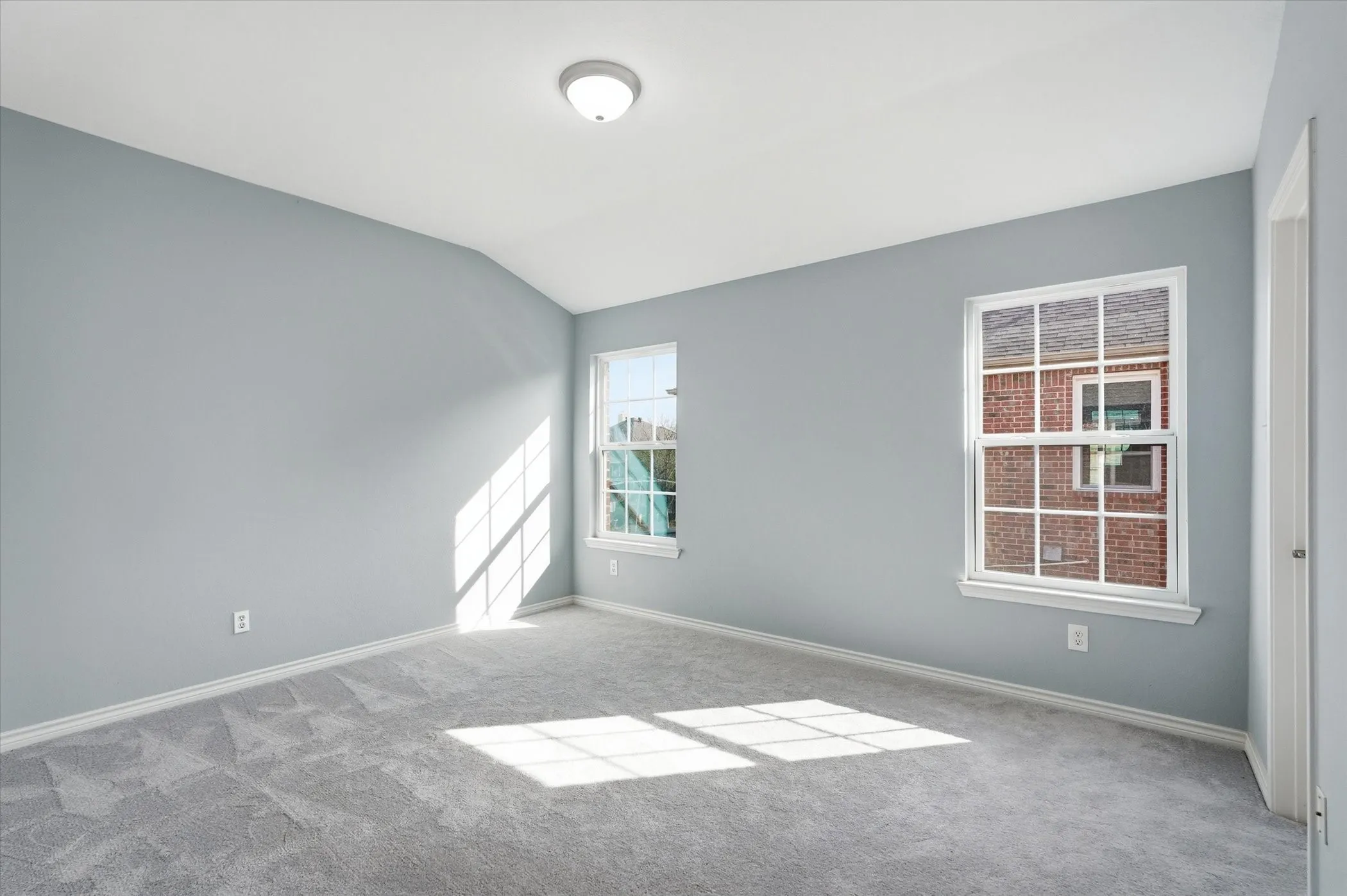 Empty room with lofted ceiling and light carpet