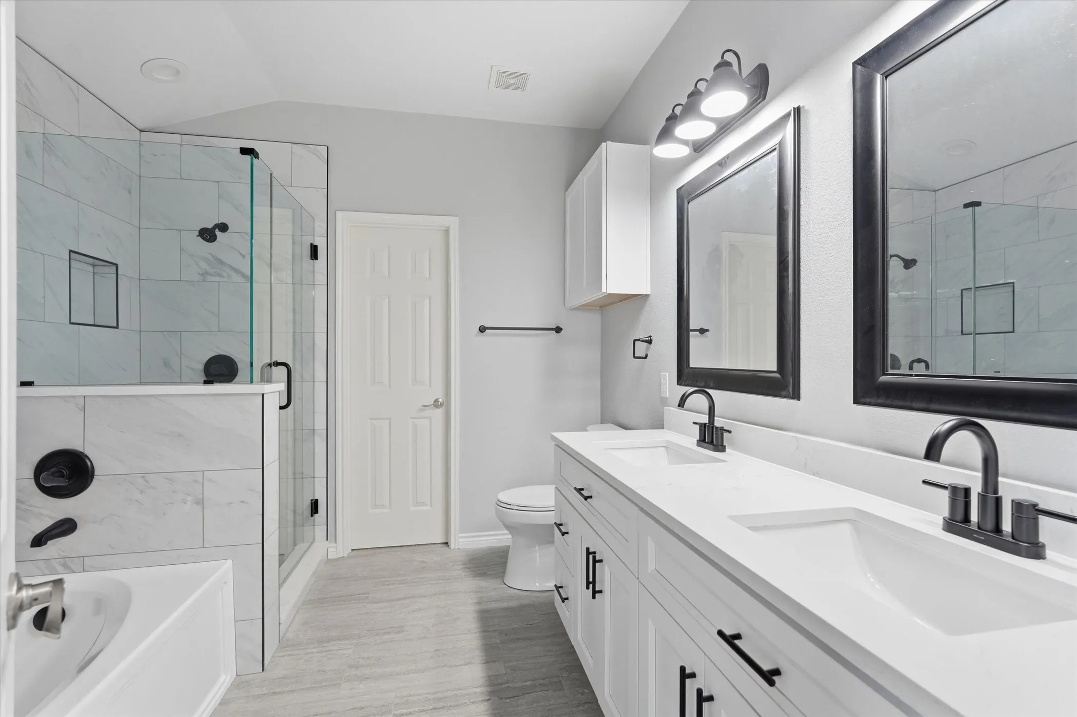 Full bathroom featuring double vanity, a bath, a shower stall, and vaulted ceiling