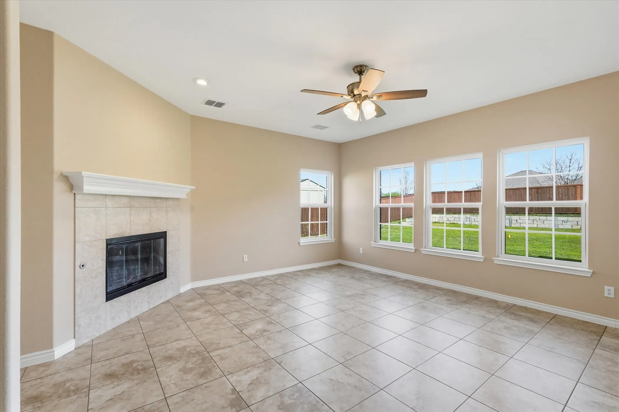 Unfurnished living room featuring ceiling fan, a tiled fireplace, light tile patterned floors, and recessed lighting