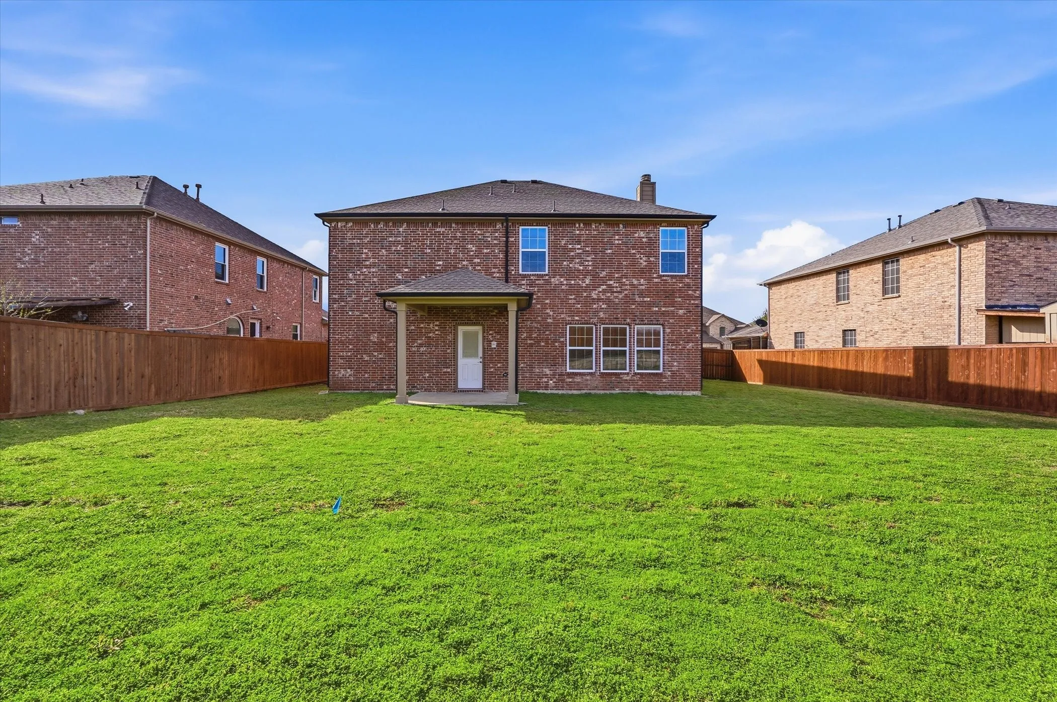 Rear view of house with a patio, brick siding, a chimney, and a fenced backyard