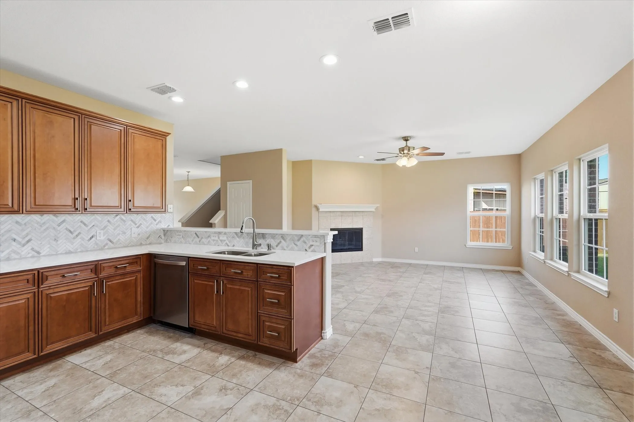 Kitchen featuring a fireplace, backsplash, a peninsula, dishwasher, and recessed lighting