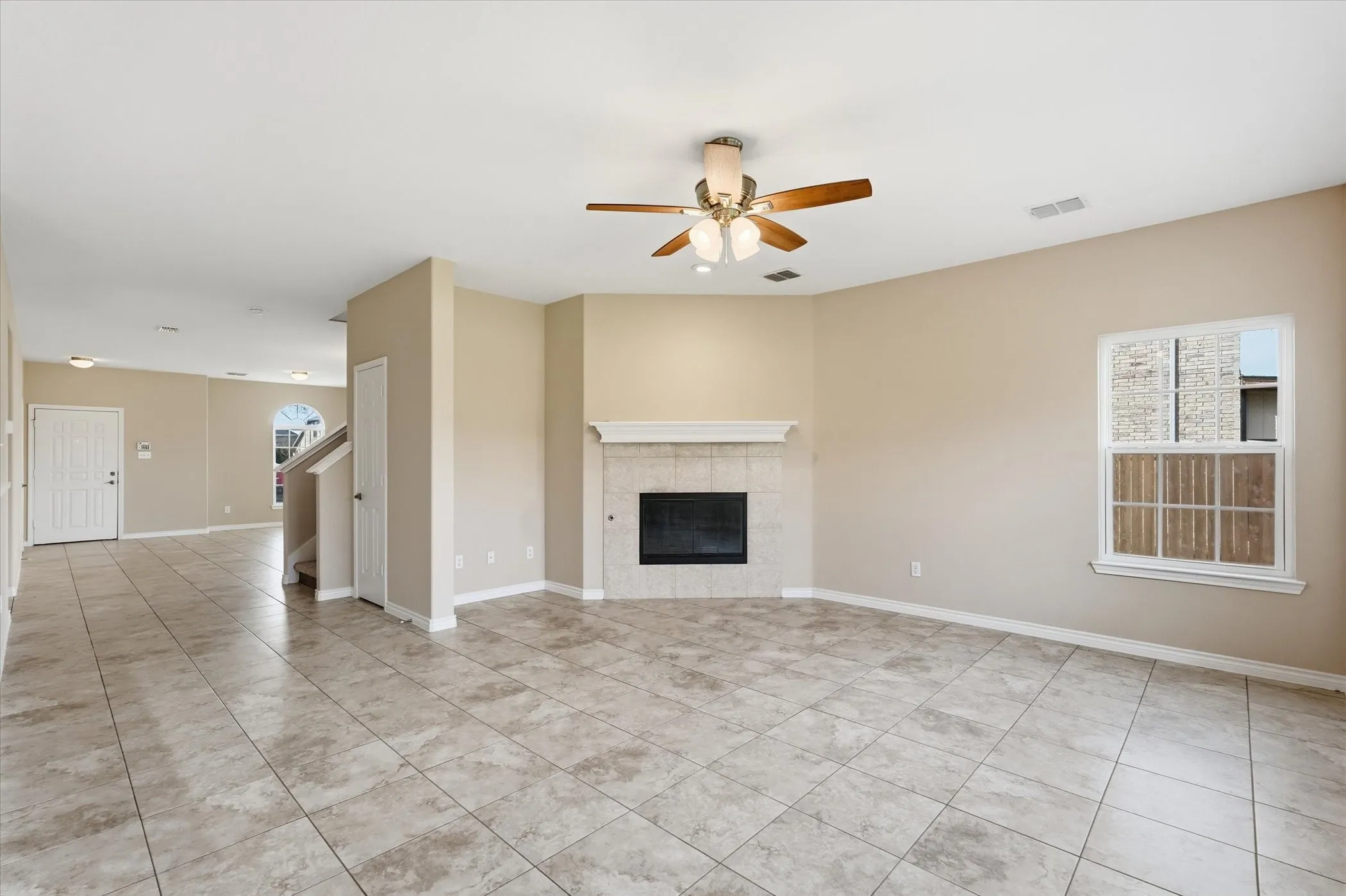 Unfurnished living room featuring ceiling fan, a tile fireplace, and light tile patterned floors