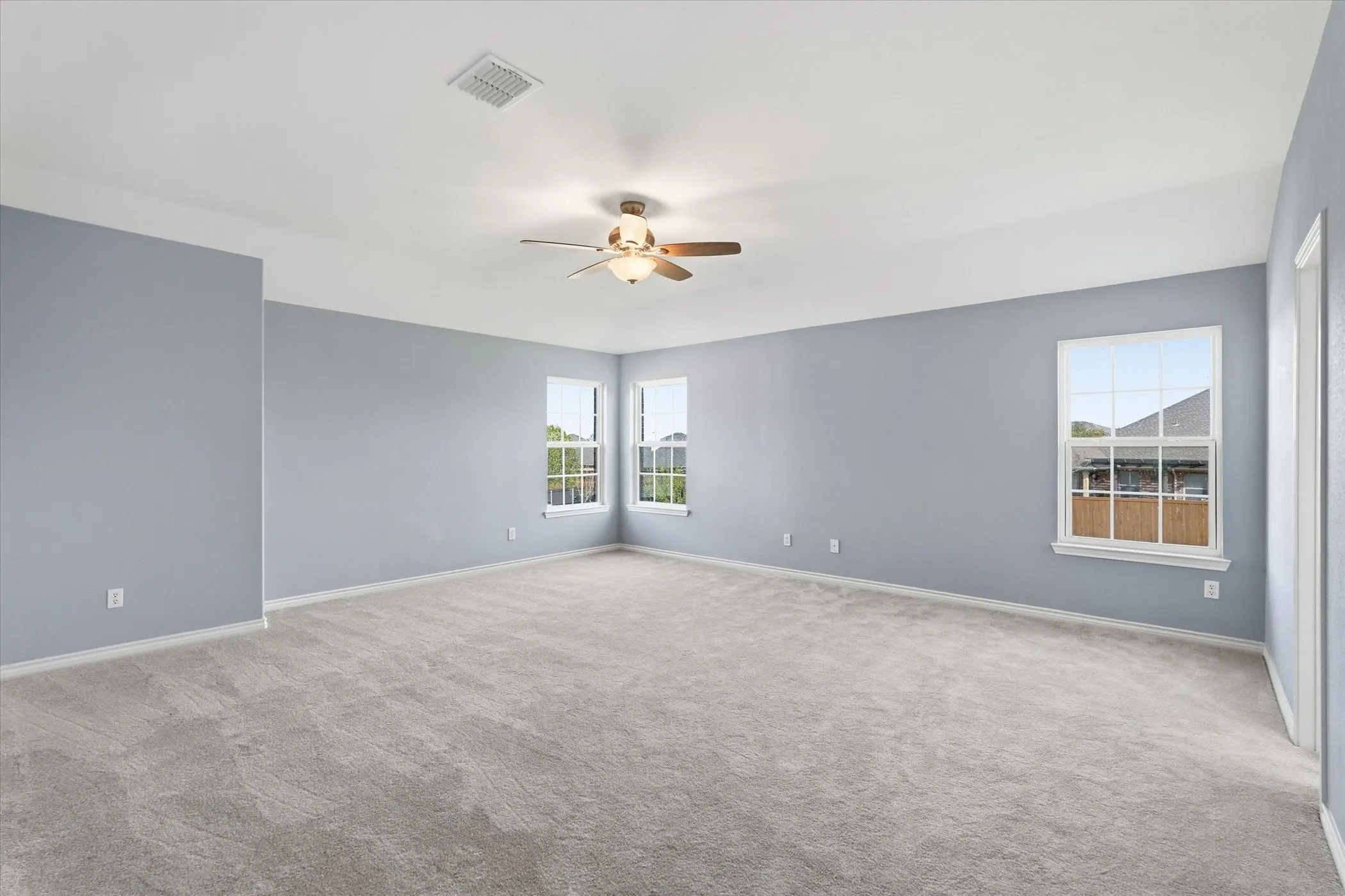 Unfurnished room featuring a ceiling fan, plenty of natural light, and light carpet