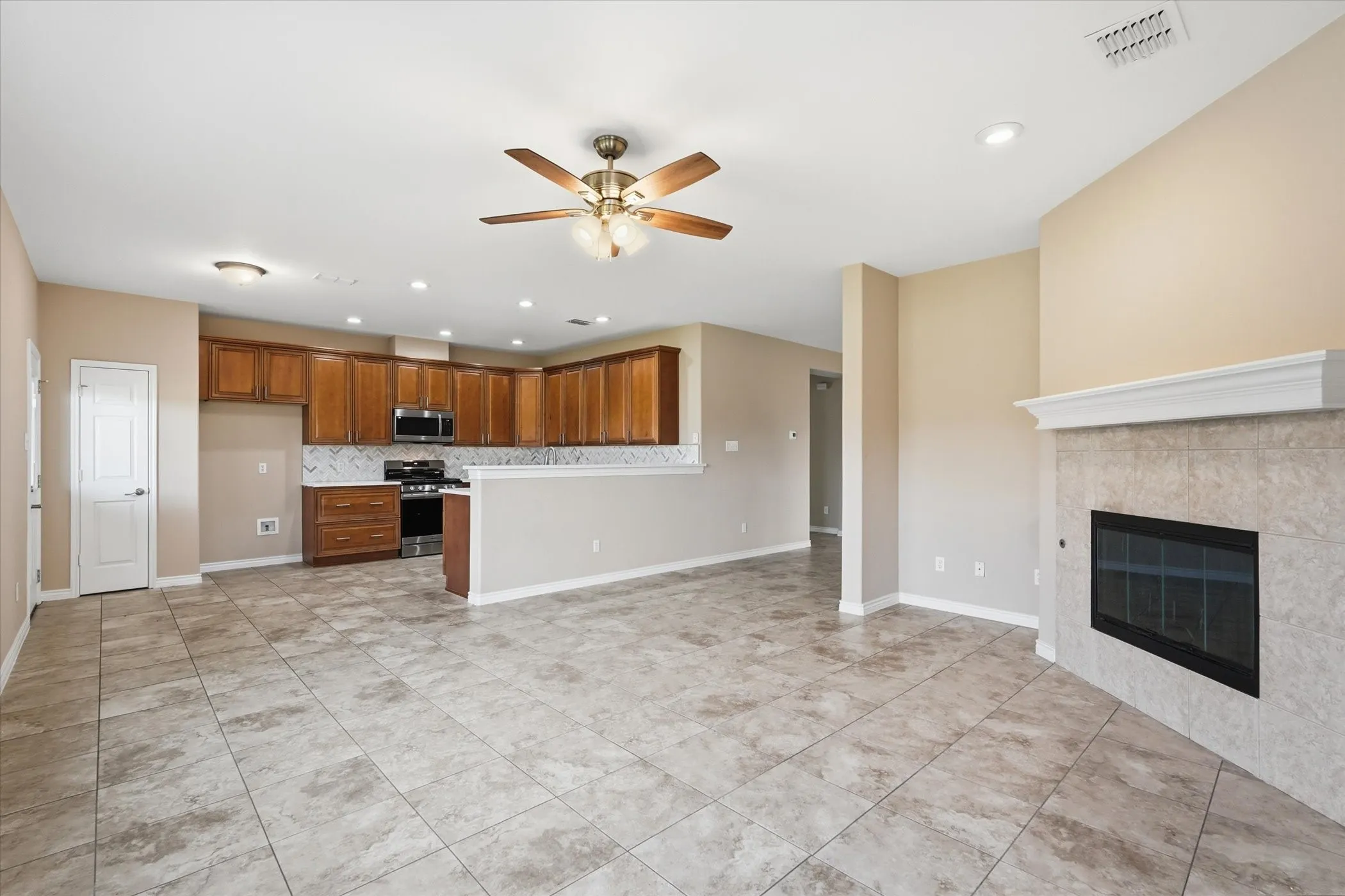 Kitchen featuring open floor plan, ceiling fan, wood finish cabinetry, light countertops, and recessed lighting